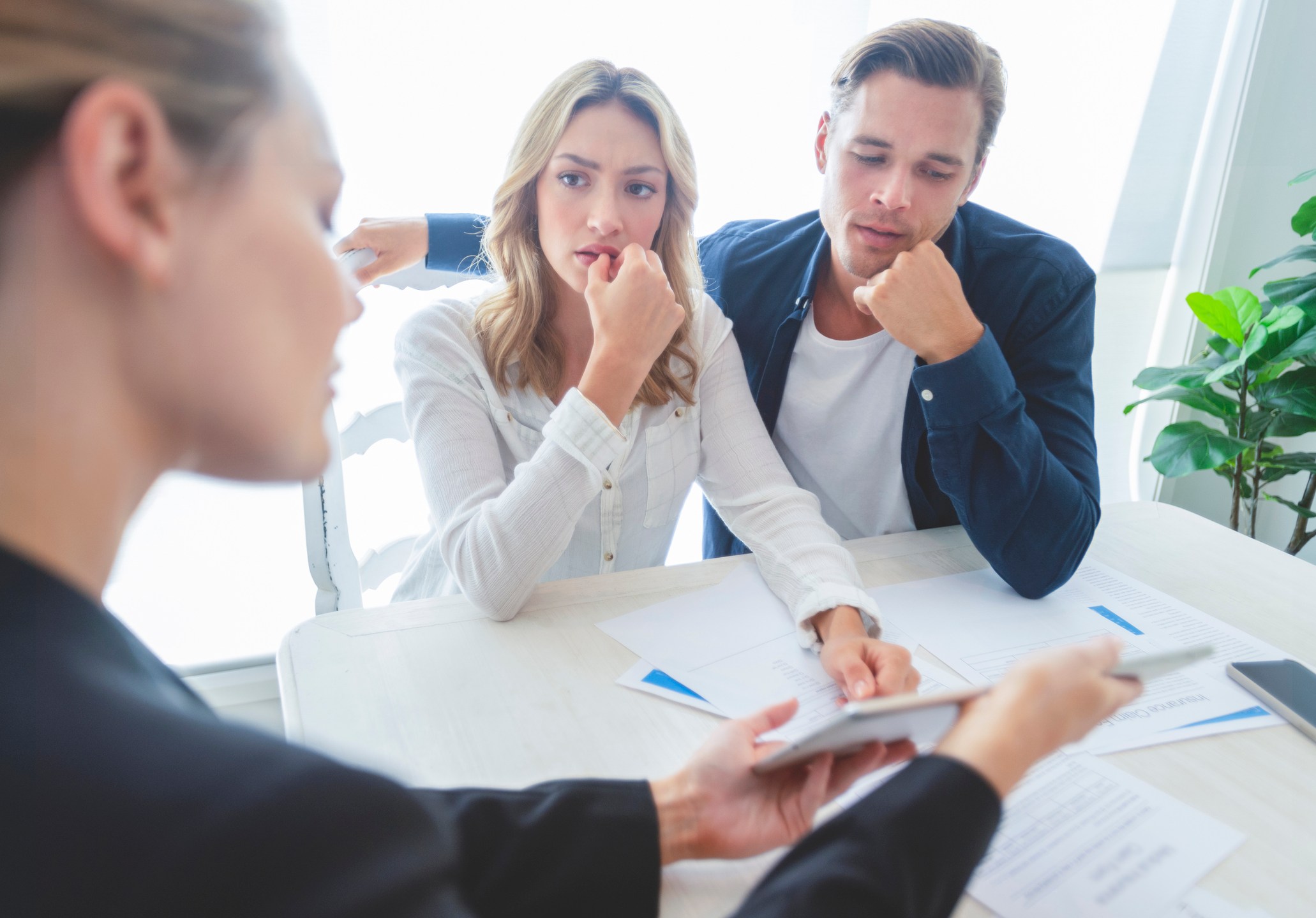 Real estate agent with couple looking through documents.