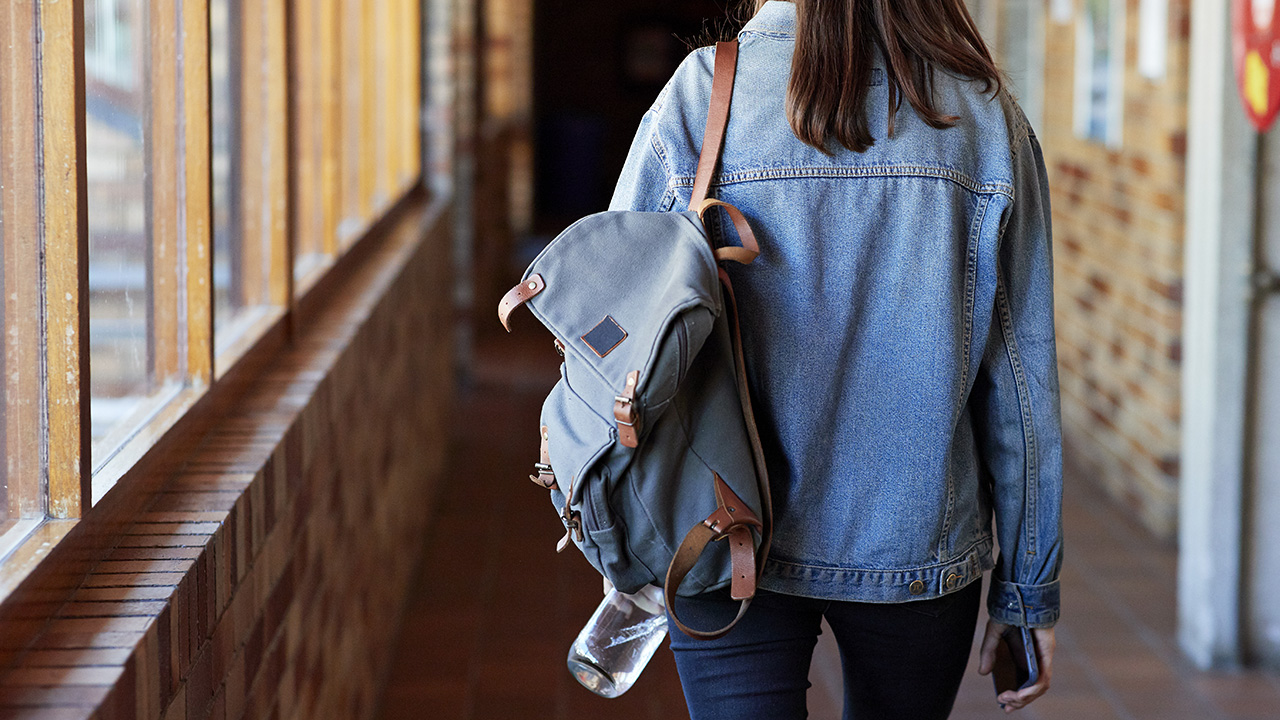 Young woman with backpack walking in corridor