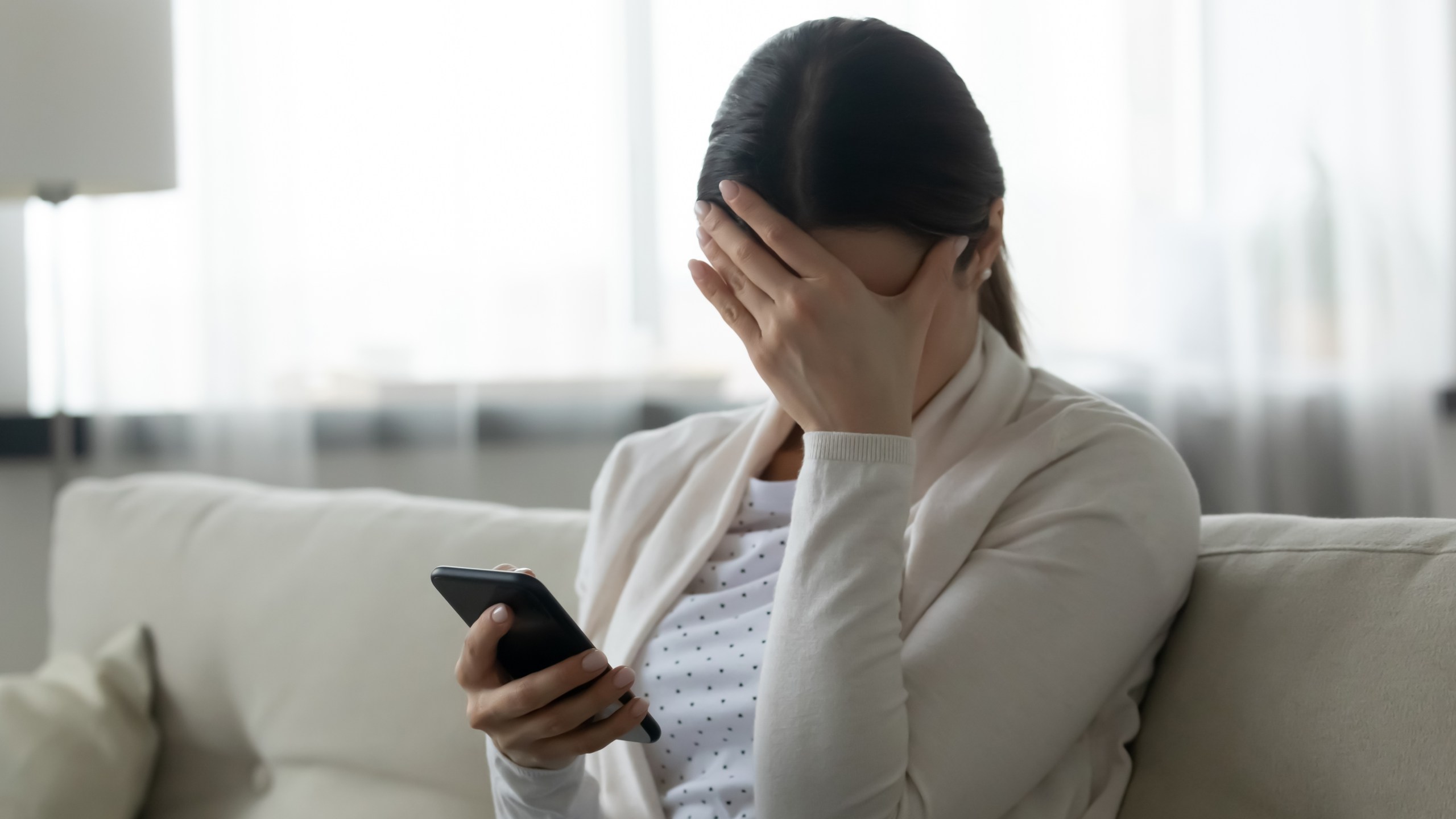 Stressed woman holding smartphone feels humiliated - stock photo