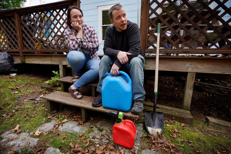 A couple sitting on the steps to a porch with fuel cans