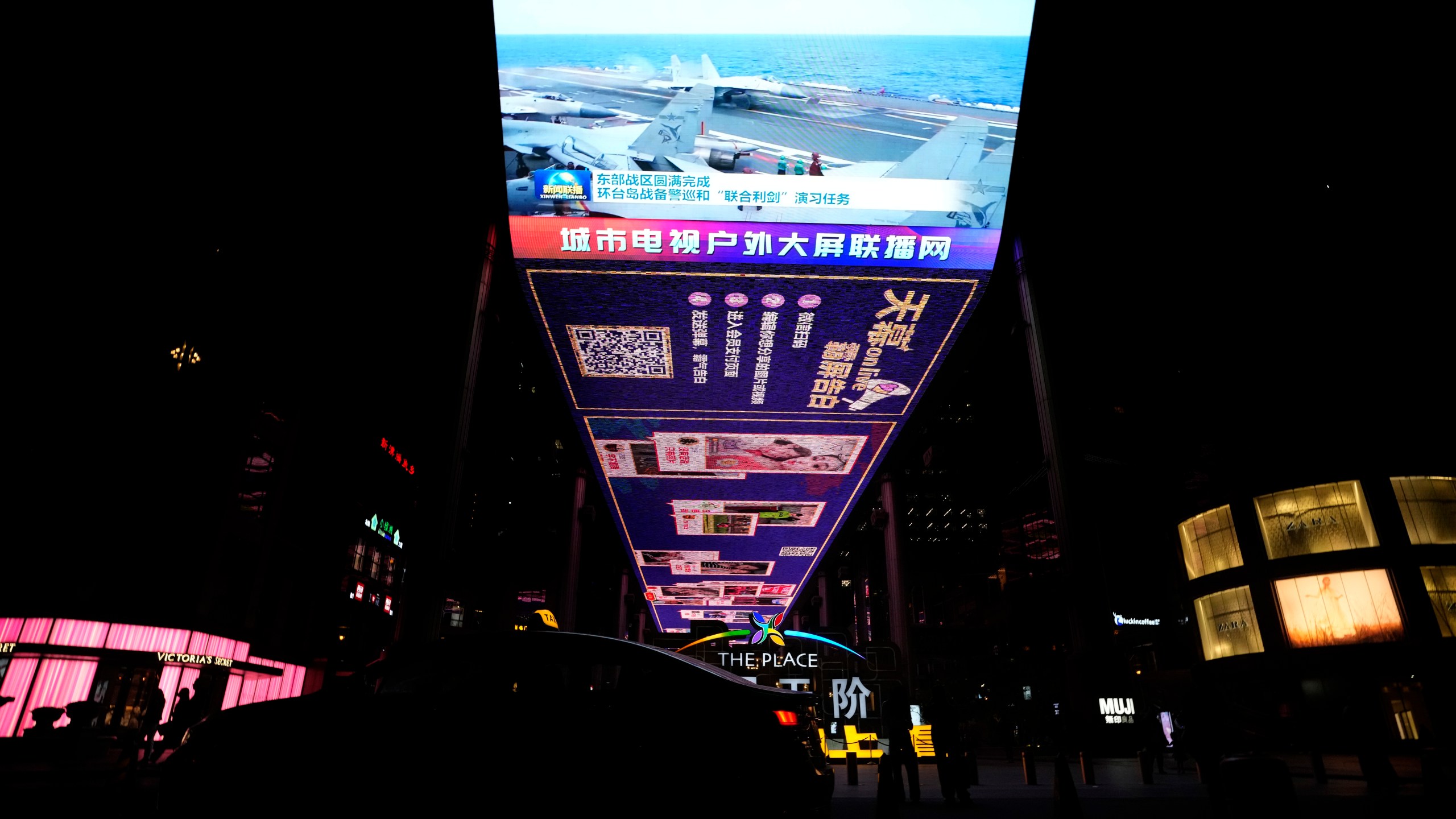 The evening news broadcast shows Chinese fighter jets on an aircraft carrier with the Chinese subtitles "Eastern Battle District successfully concludes the patrol exercise around the taiwan island and Joint Sword exercise" on an outdoor screen in Beijing, Monday, April 10, 2023. China's military declared Monday it is "ready to fight" after completing three days of large-scale combat exercises around Taiwan that simulated sealing off the island in response to the Taiwanese president's trip to the U.S. last week. (AP Photo/Ng Han Guan)