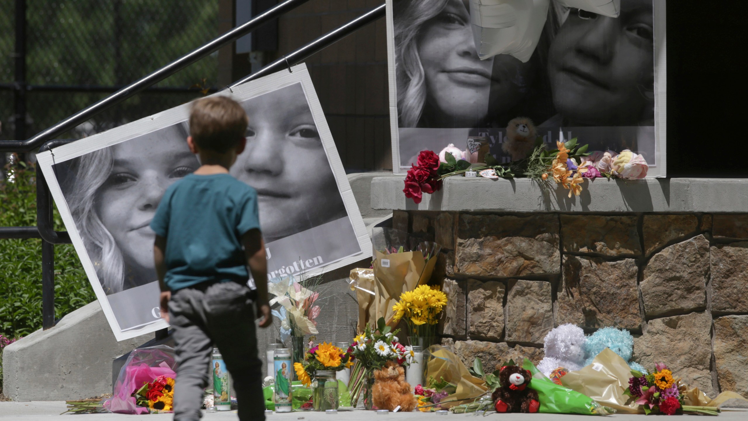 FILE - A boy looks at a memorial for Tylee Ryan and Joshua "JJ" Vallow in Rexburg, Idaho, on June 11, 2020. The investigation started roughly 29 months ago with two missing children. It soon grew to encompass five states, four suspected murders and claims of an unusual, doomsday-focused religious beliefs involving "dark spirits" and "zombies." On Monday, April 10, 2023, an Idaho jury will begin the difficult task of deciding the veracity of those claims and others in the triple murder trial of Lori Vallow Daybell. (John Roark/The Idaho Post-Register via AP, File)