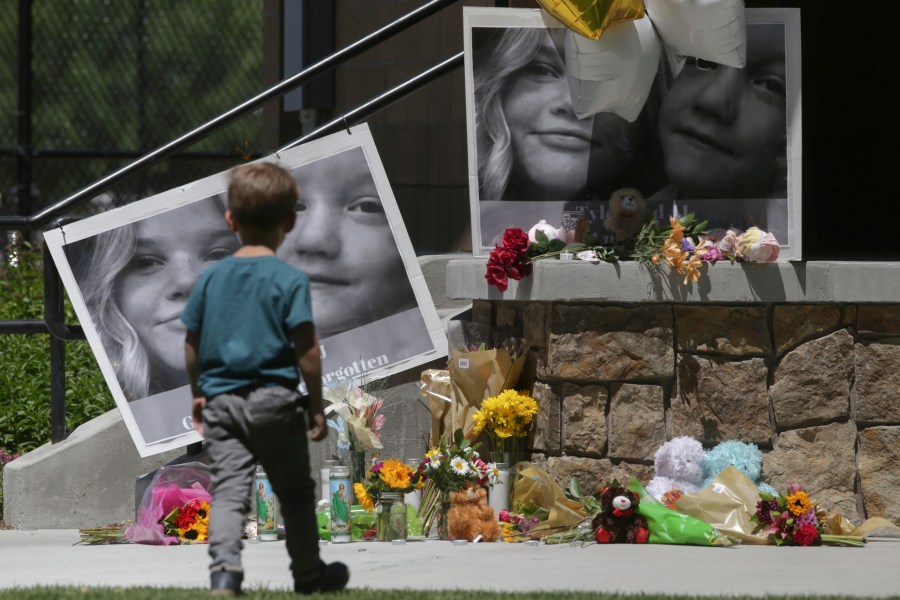 FILE - A boy looks at a memorial for Tylee Ryan and Joshua "JJ" Vallow in Rexburg, Idaho, on June 11, 2020. The investigation started roughly 29 months ago with two missing children. It soon grew to encompass five states, four suspected murders and claims of an unusual, doomsday-focused religious beliefs involving "dark spirits" and "zombies." On Monday, April 10, 2023, an Idaho jury will begin the difficult task of deciding the veracity of those claims and others in the triple murder trial of Lori Vallow Daybell. (John Roark/The Idaho Post-Register via AP, File)