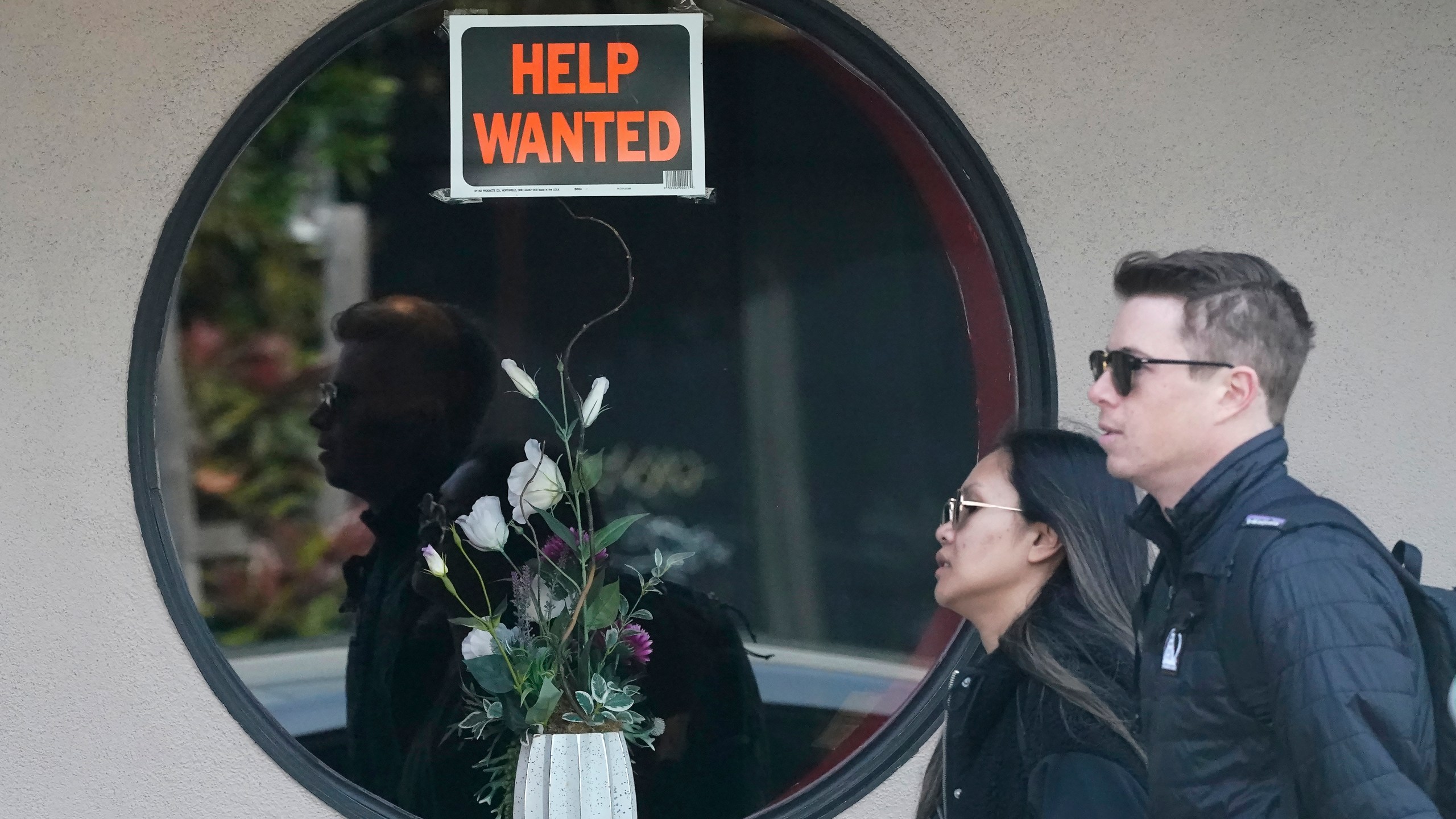 Pedestrians walk past a help wanted sign posted on the door of a restaurant in San Francisco, Tuesday, April 18, 2023. On Thursday, the Labor Department reports on the number of people who applied for unemployment benefits last week. (AP Photo/Jeff Chiu)