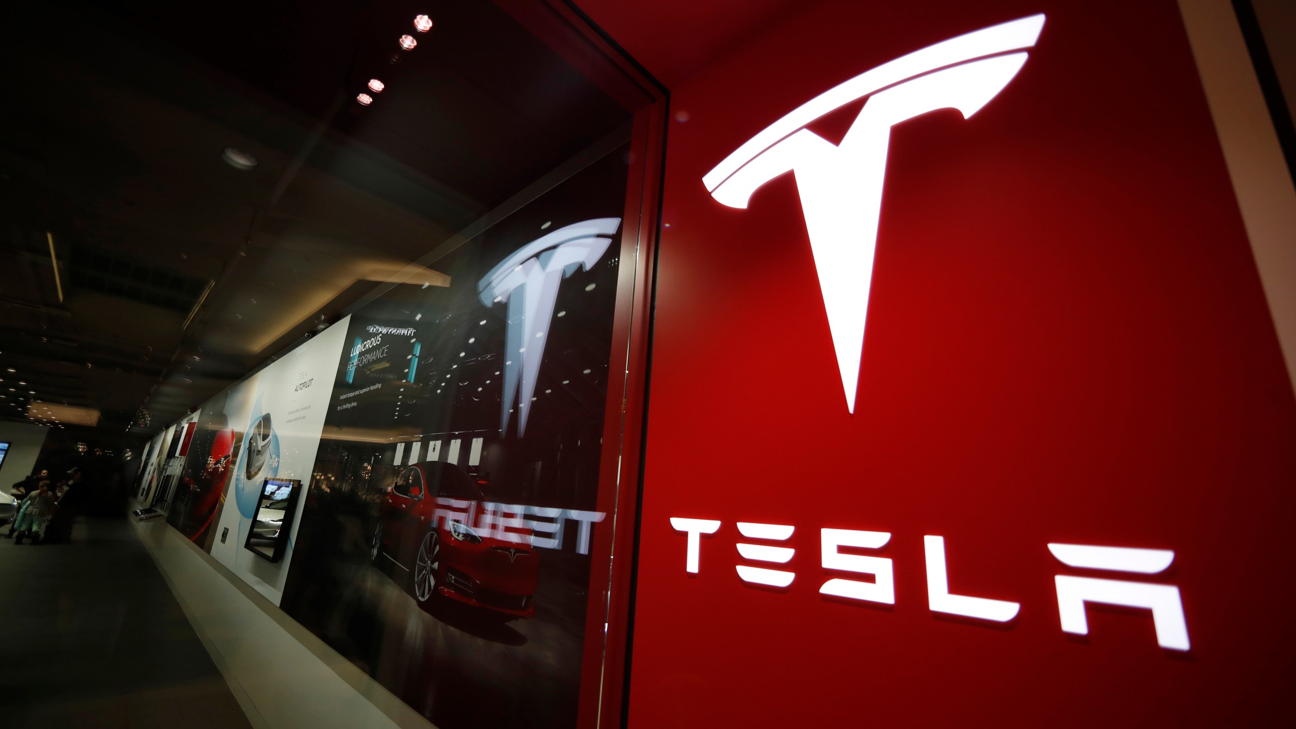 FILE - A sign bearing the Tesla company logo is displayed outside a Tesla store in Cherry Creek Mall in Denver, Colorado, Feb. 9, 2019. Tesla's first-quarter vehicle sales in 2023 rose 36% after the company cut prices twice in a bid to stimulate demand. (AP Photo/David Zalubowski, File)