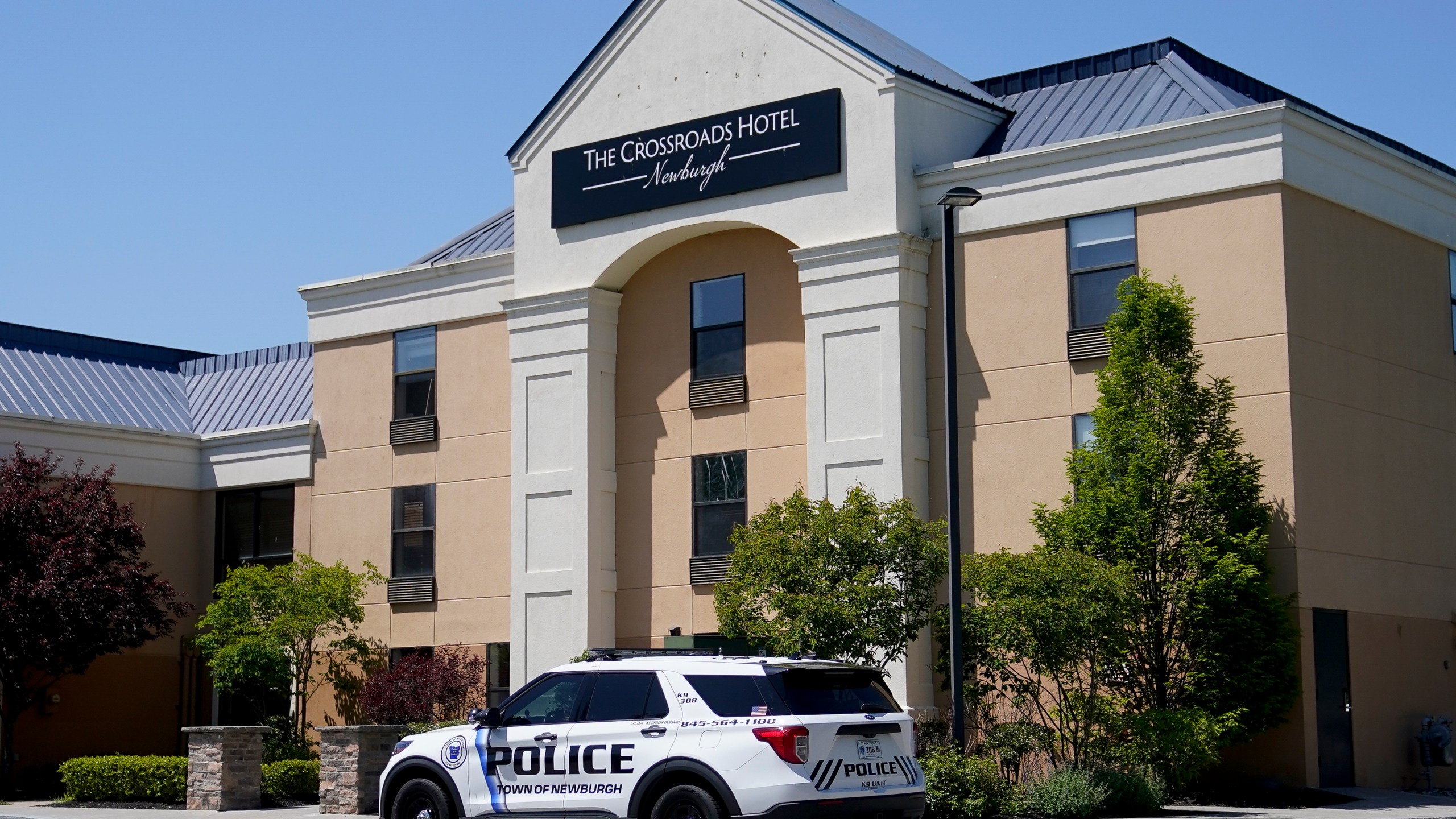 A Town of Newburgh police vehicle is parked outside The Crossroads Hotel where two busloads of migrants arrived hours earlier, Thursday, May 11, 2023, in Newburgh, N.Y. New York City Mayor Eric Adams touched off a furor north of the city by announcing last week that the city would temporarily send north up to 300 single, adult men to two hotels in suburban Rockland County and neighboring Orange County. (AP Photo/John Minchillo)