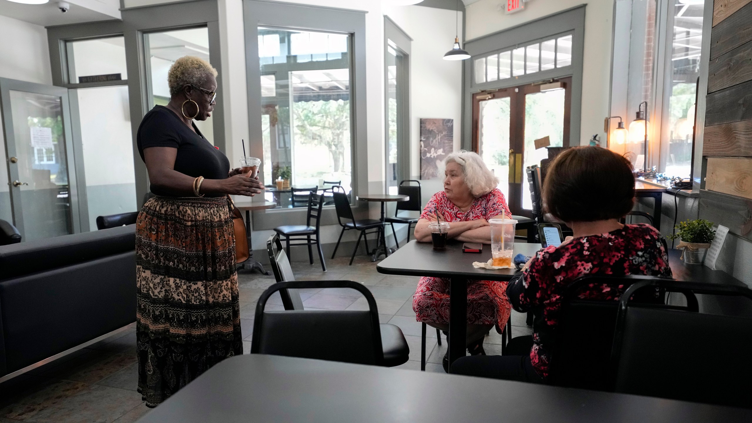 FILE - Betty Shinn talks to a neighbor and her neighbor's friend at a coffee shop in in Mobile, Ala., June 2, 2023. A U.S. Supreme Court decision a decade ago that tossed out the heart of the Voting Rights Act continues to reverberate across the country. Republican-led states continue to pass voting restrictions that, in several cases, would have been subject to federal review had the court left the provision intact. Alabama could add another to the list soon, one that would make it a crime to help a non-family member fill out or return an absentee ballot. "This is voter suppression at its best," said Shinn, who recently testified against the bill during a legislative hearing in Montgomery. "It's no different from asking me how many jellybeans are in that jar or asking me to recite the Constitution from memory." (AP Photo/Gerald Herbert)