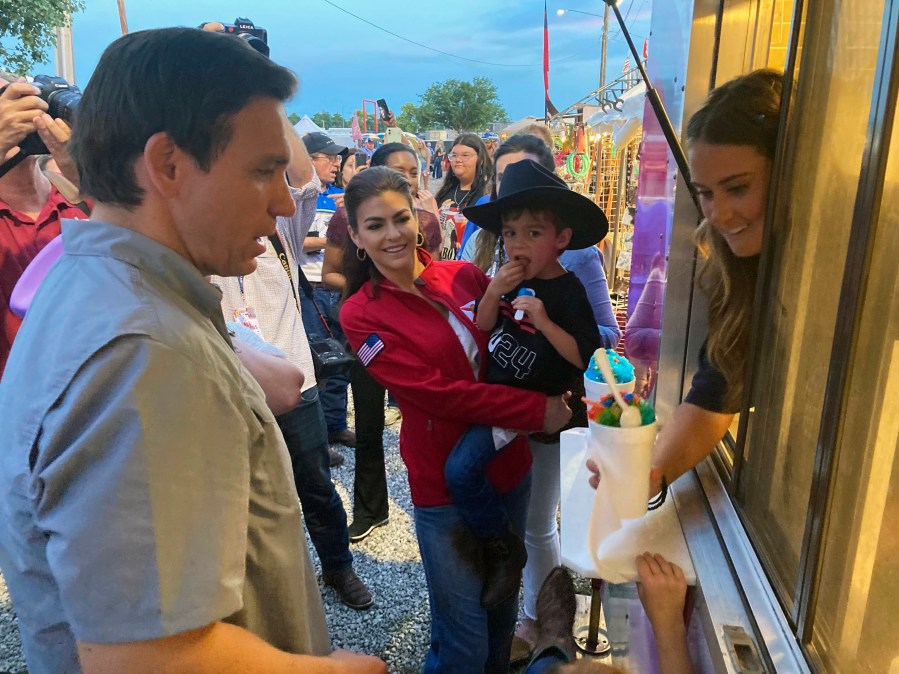 Casey DeSantis, center, and son Mason watch as husband and father, Republican presidential candidate and Florida Gov. Ron DeSantis orders snow cones for the family, at the rodeo, in Ponca, Okla., Saturday, June 10, 2023. (AP Photo/Thomas Beaumont)