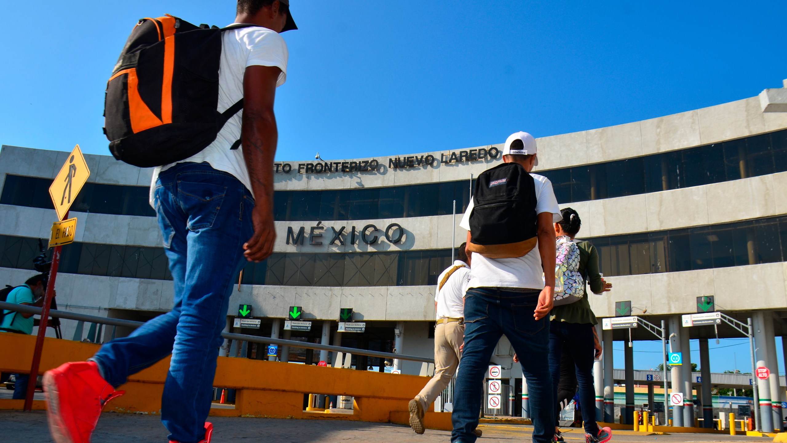 U.S. asylum-seekers being returned by U.S. authorities under the so-called Remain in Mexico program are escorted by a Mexican migration agent as they walk back into Nuevo, Laredo Mexico, across the international bridge from Laredo, Texas, Wednesday, July 10, 2019. The Biden administration has stopped taking appointments via its mobile phone app from asylum seekers in a notoriously dangerous and corrupt Mexican border city amid signs migrants who used it were being targeted for extortion.(AP Photo/Salvador Gonzalez)