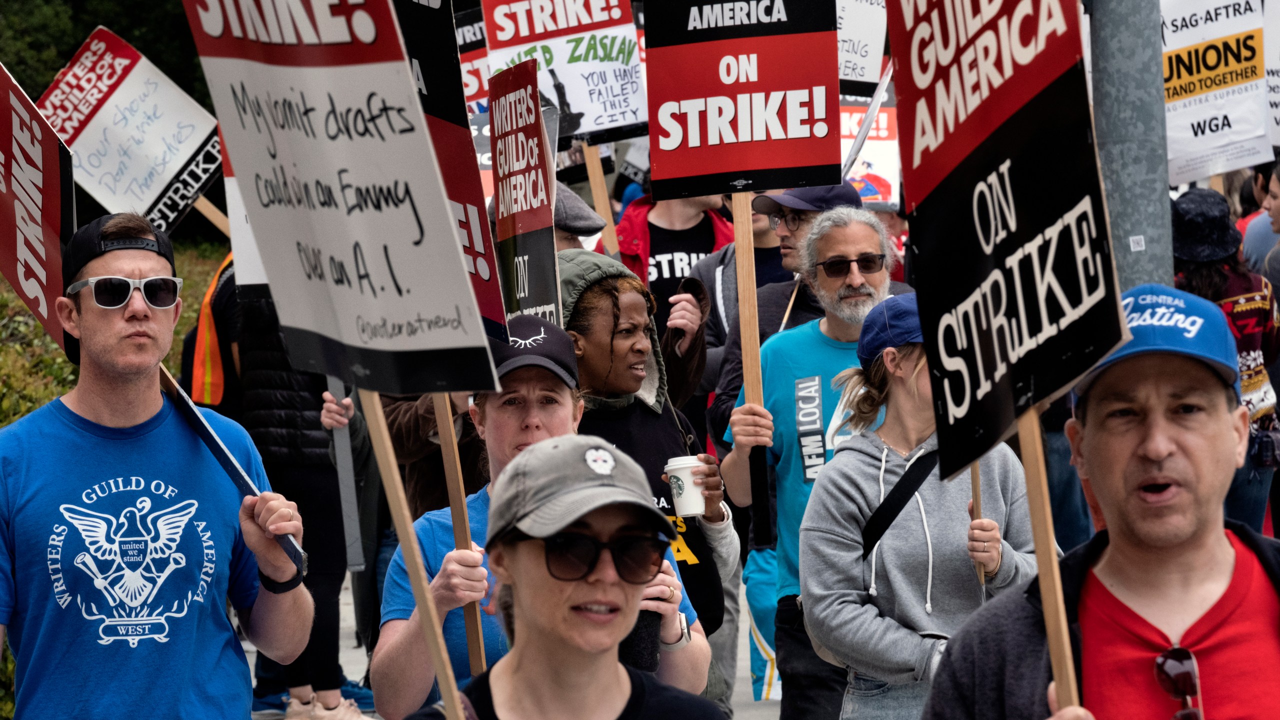 FILE -Picketers pass near a studio entrance during a Writers Guild rally outside Warner Bros. Studios, Wednesday, May 24, 2023, in Burbank, Calif. As a strike drags on, about 1,000 Hollywood writers and their supporters have marched and rallied in Los Angeles for a new contract with studios that includes the payment guarantees and job security they say they deserve. Speakers at Wednesday's event on June 21, emphasized the solidarity the Writers Guild of America has received from other unions. (AP Photo/Richard Vogel, File)