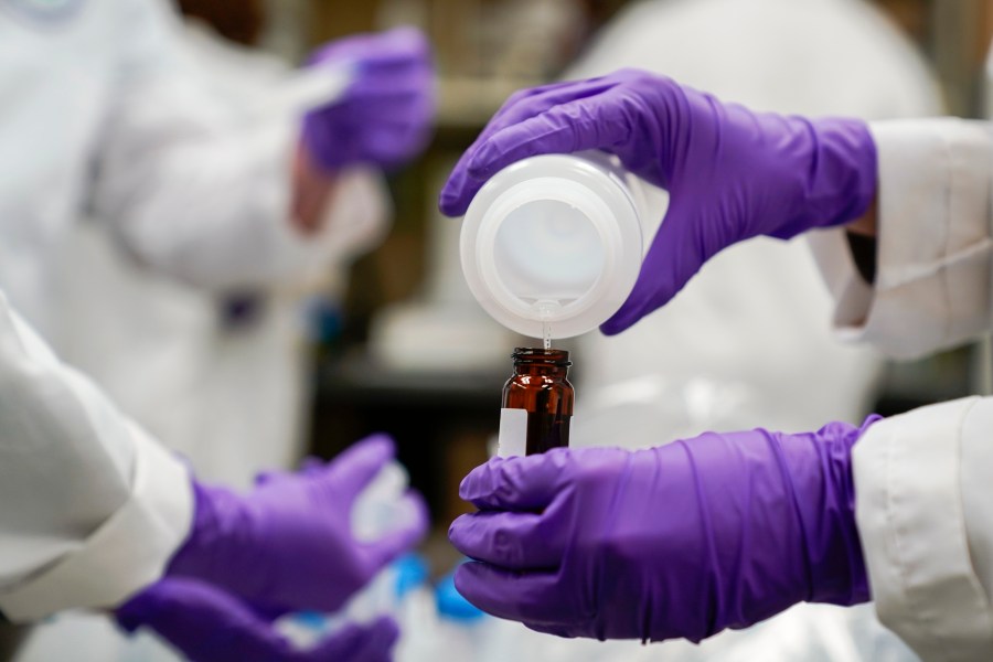 FILE - Eva Stebel, water researcher, pours a water sample into a smaller glass container for experimentation as part of drinking water and PFAS research at the U.S. Environmental Protection Agency Center For Environmental Solutions and Emergency Response on Feb. 16, 2023, in Cincinnati. The 3M chemical company announced Thursday, June, 22, 2023 a $10.3 billion settlement with U.S. water utilities and agencies over PFAS pollution that will allow them to test and treat drinking water contaminated with these “forever chemicals.(AP Photo/Joshua A. Bickel, File)