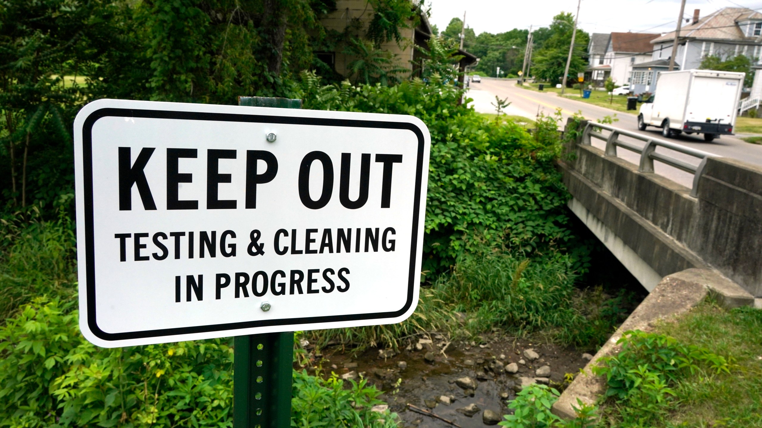 A warning sign is posted near a stream in East Palestine Park in East Palestine, Ohio on Thursday, June 22, 2023. An investigative hearing is being held by the National Transportation and Safety Board in East Palestine over two days, to investigate the Feb. 3, 2023, Norfolk Southern Railway train derailment and subsequent hazardous material release and fires. (AP Photo/Gene J. Puskar)