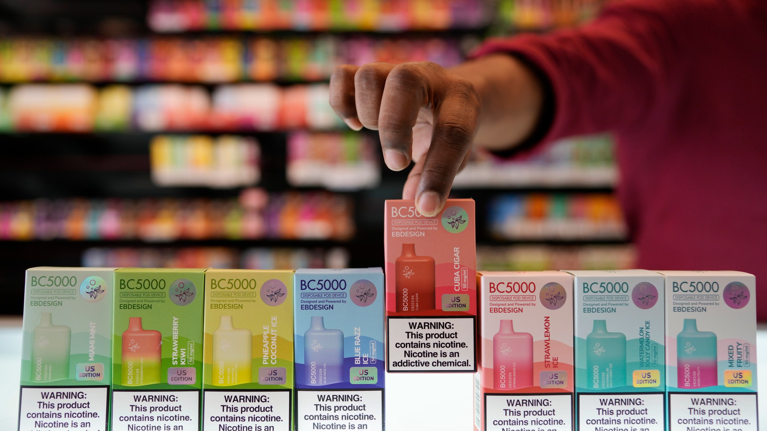 An employee displays some of the varieties of disposable electronic cigarette devices manufactured by EB Design, formerly known as Elf Bar, at Vapes N Smoke in Pinecrest, Fla., Monday, June 26, 2023. Since 2020, the number of different e-cigarette devices for sale in the U.S. has exploded to more than 9,000, a nearly three-fold increase driven almost entirely by a wave of disposable vapes from China. (AP Photo/Rebecca Blackwell)