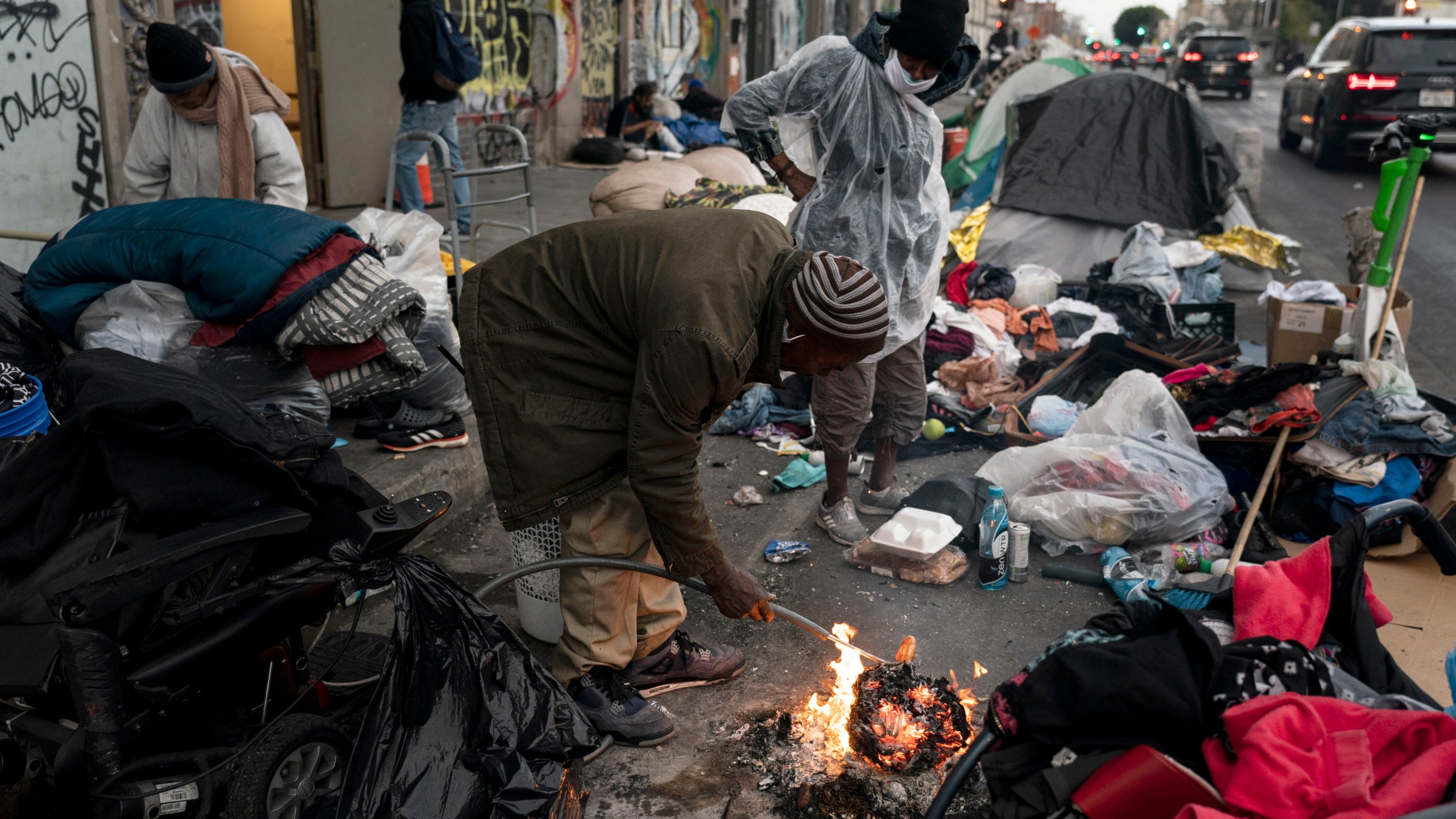 FILE - Robert Mason, a 56-year-old homeless man, warms up a piece of doughnut over a bonfire he set to keep himself warm on Skid Row in Los Angeles, on Feb. 14, 2023. The number of homeless residents counted in Los Angeles County spiked again, increasing by 9% since last year in the latest marker of how deep the crisis is of people sleeping in cars, encampments or shelters in California. (AP Photo/Jae C. Hong, File)