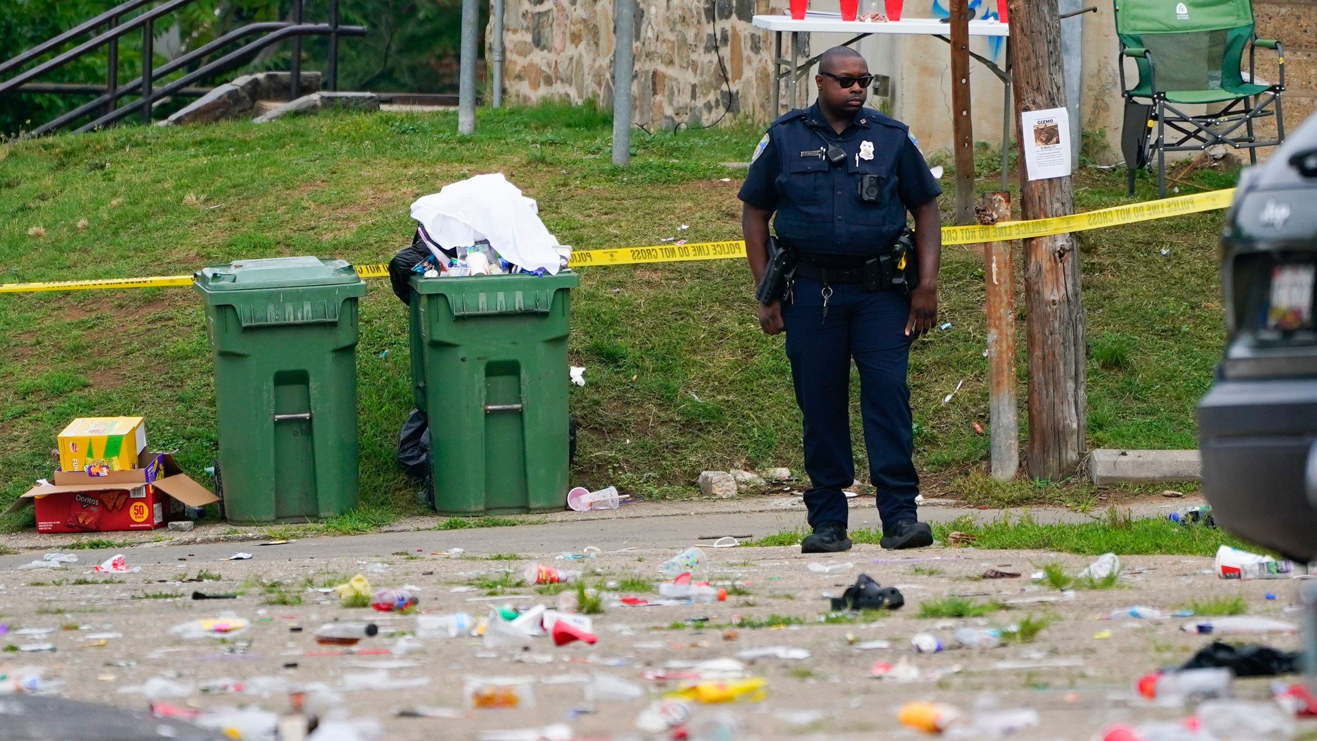 A police officer stands in the area of a mass shooting incident in the Southern District of Baltimore, Sunday, July 2, 2023. Police say a number of people were killed and dozens were wounded in a mass shooting that took place during a block party just after midnight. (AP Photo/Julio Cortez)