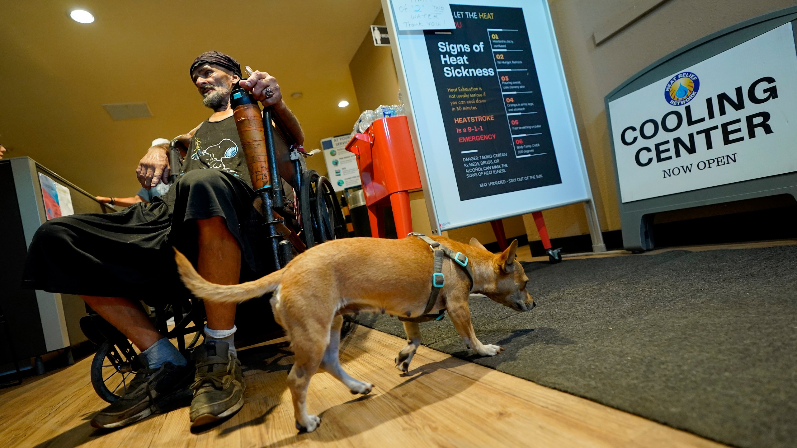 Charles Sanders, 59, and his dog Babygirl, cool off inside the Justa Center, Friday, July 14, 2023, in downtown Phoenix. Sanders, from Denver, has been spending the days at the center, a day center for homeless people 55 years and older in the downtown area. Several dozen people stop by daily for cold water, a meal, a shower and an electrical outlet to charge a mobile phone. (AP Photo/Matt York)