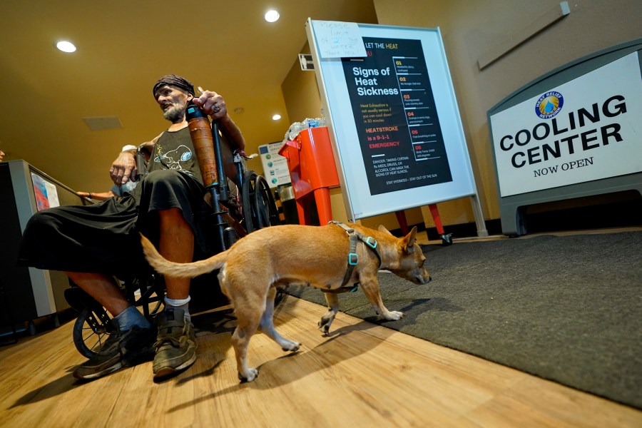 Charles Sanders, 59, and his dog Babygirl, cool off inside the Justa Center, Friday, July 14, 2023, in downtown Phoenix. Sanders, from Denver, has been spending the days at the center, a day center for homeless people 55 years and older in the downtown area. Several dozen people stop by daily for cold water, a meal, a shower and an electrical outlet to charge a mobile phone. (AP Photo/Matt York)