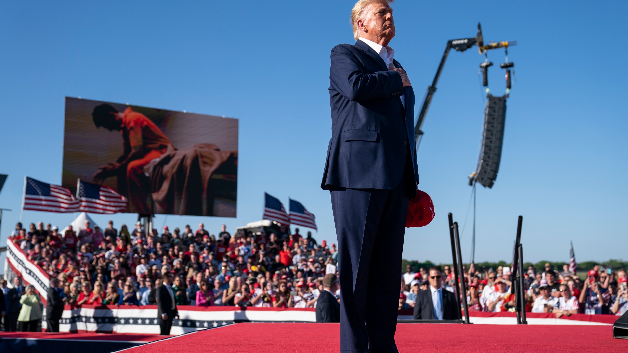 FILE - Former President Donald Trump stands while a song, "Justice for All," is played during a campaign rally at Waco Regional Airport, March 25, 2023, in Waco, Texas. The song features a choir of men imprisoned for their role in the Jan. 6, 2021, insurrection at the U.S. Capitol singing the national anthem and a recording of Trump reciting the Pledge of Allegiance. (AP Photo/Evan Vucci)