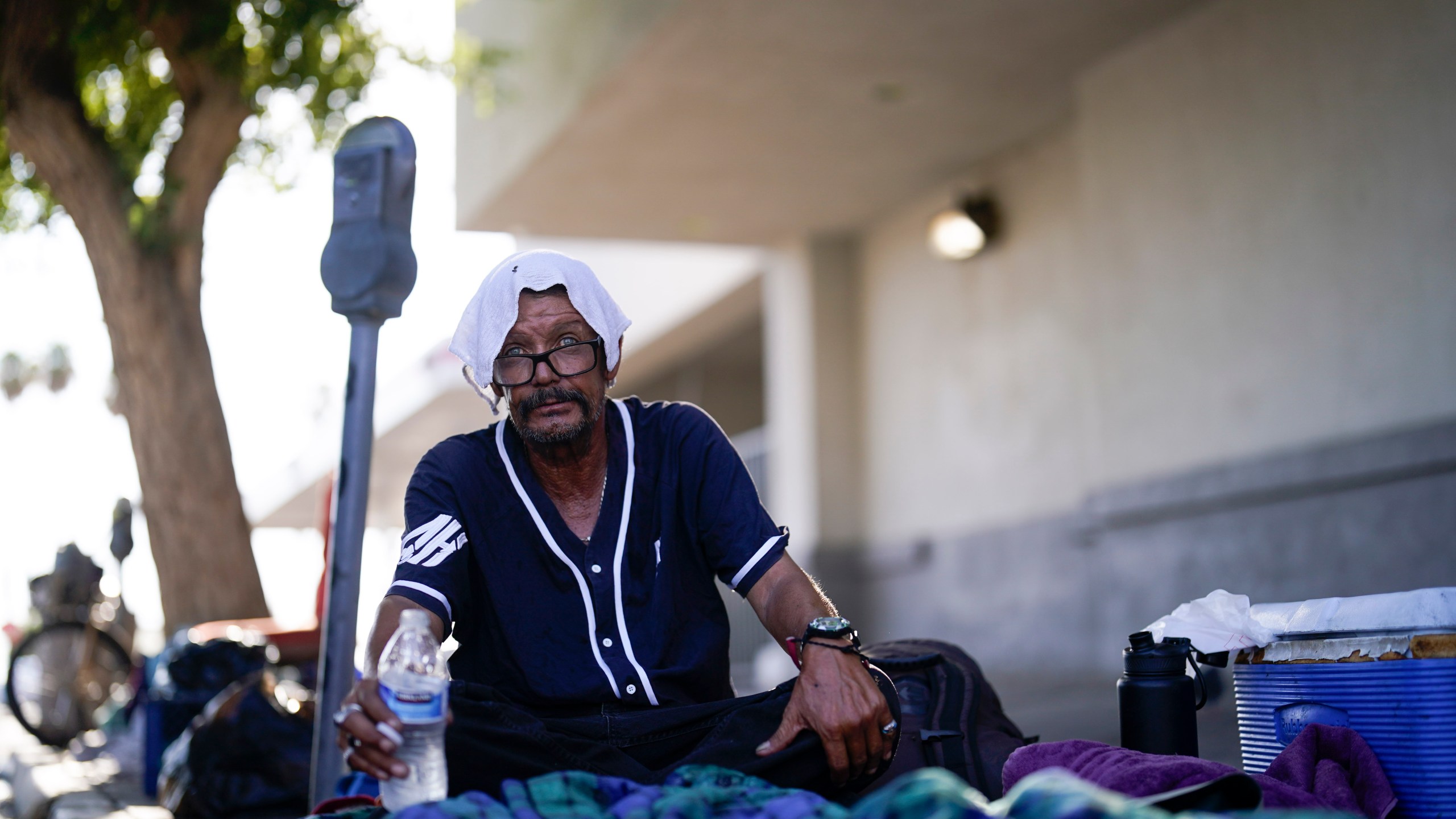 FILE - A man, who is homeless, drinks water as he wears a wet towel on his head, given to him by Maribel Padilla of the Brown Bag Coalition, July 20, 2023, in Calexico, Calif. Once temperatures hit 113 degrees Fahrenheit (45 Celsius), Padilla and the Brown Bag Coalition meet up with people who are homeless in Calexico, providing them with a cold, wet towel, and some refreshments to help them endure the scorching temperatures. (AP Photo/Gregory Bull, File)