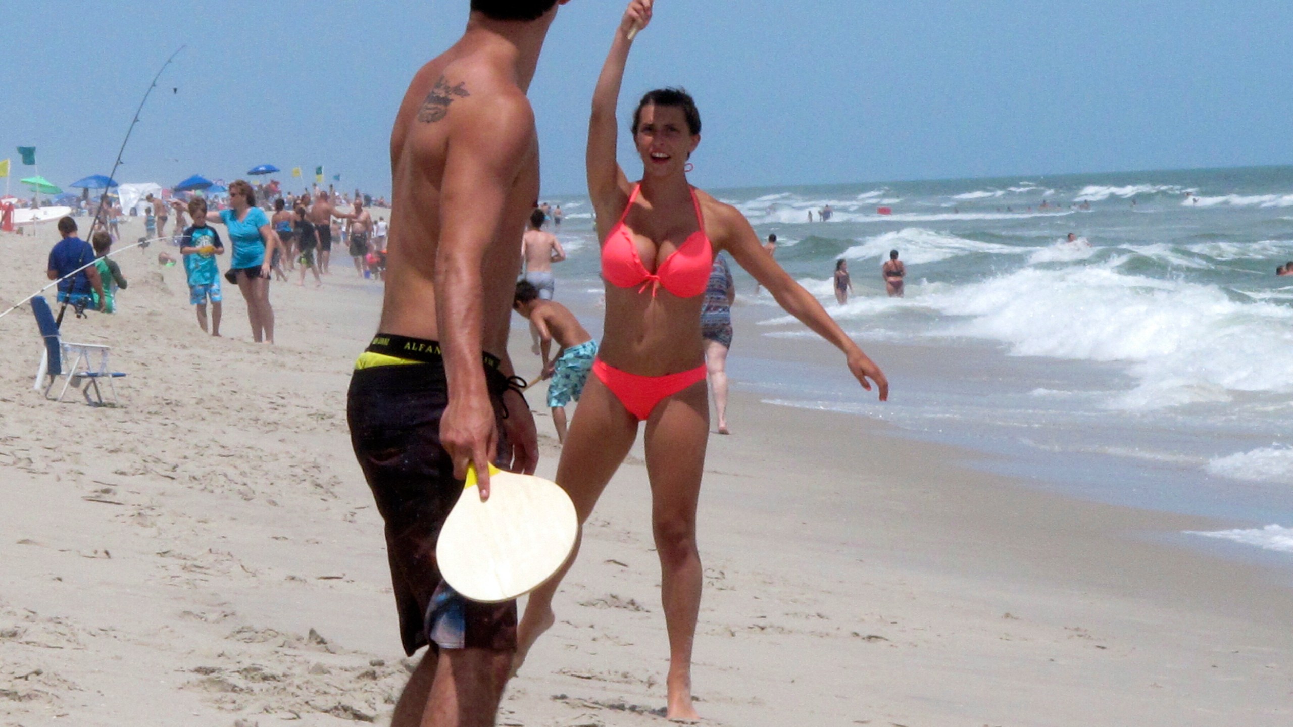 Beachgoers play paddle ball on the beach in Ship Bottom, N.J. on June 30, 2014. On Aug. 4, 2023, a German wind power company and a New York utility applied for permission to build a wind farm 37 miles off the coast of Long Beach Island, far enough out to sea that it could not be seen from the beach. (AP Photo/Wayne Parry)