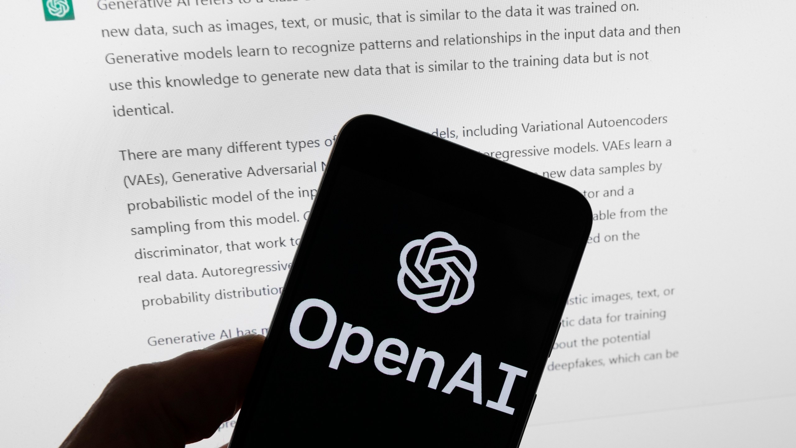 FILE - The OpenAI logo is seen on a mobile phone in front of a computer screen displaying output from ChatGPT, March 21, 2023, in Boston. Several news organizations, writers and photographers groups are seeking regulations to govern the fast-moving artificial intelligence technology that threatens upheavals for their businesses. In an open letter sent on Wednesday, Aug. 9, 2023, outlined priorities for setting rules on the technology, which is developing faster than regulators can keep up with. (AP Photo/Michael Dwyer, File)