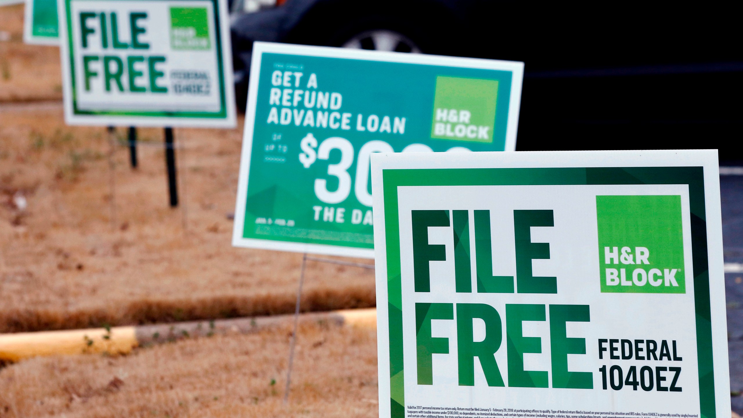 FILE- In this Feb. 14, 2018, file photo, H&R Block signs are displayed in Jackson, Miss. Congressional Democrats are accusing big tax preparation firms including Intuit and H&R Block of undermining the federal government's upcoming electronic free-file tax return system, and are demanding lobbying, hiring and revenue data to determine what's going on. (AP Photo/Rogelio V. Solis, File)