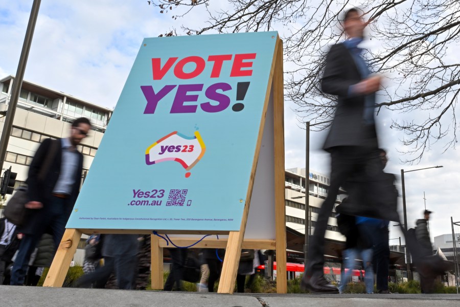 Commuters walk past a vote "yes" stand for the upcoming Voice referendum at the Civic Bus Interchange in Canberra, Australia, Wednesday, Aug. 30, 2023. Prime Minister Anthony Albanese announced that Australians will vote on Oct. 14 in a referendum that would enshrine in the nation's constitution a mechanism for Indigenous people to advise Parliament on policies that effect their lives known as the Voice. (Mick Tsikas/AAP Image via AP)