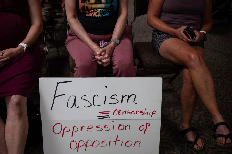 Three people sit with a sign at a Campbell County, Wyo., Library Board meeting, July 23, 2023, in Gillette, Wyo. The library system is among several local and state libraries that have cut ties with the American Library Association amid criticism that the librarian professional group, which has stood up for books some deem harmful to youngsters, has become politicized. (Ed Glazar/Gillette News Record via AP)