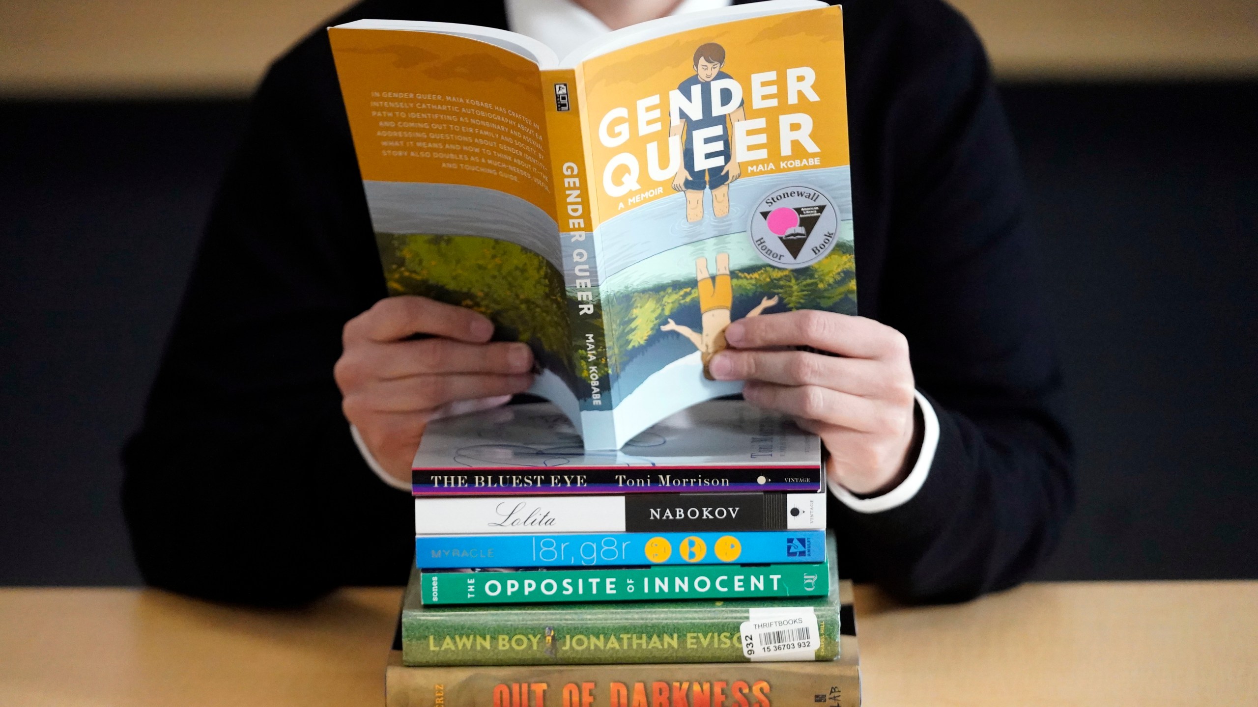 FILE - Amanda Darrow, director of youth, family and education programs at the Utah Pride Center, poses with books that have been the subject of complaints from parents on Dec. 16, 2021, in Salt Lake City. The nationwide surge in book bannings continues. The American Library Association reported Wednesday, Sept. 20, 2023, that challenges to books in schools and public libraries will likely reach record highs in 2023, topping what had been a record pace in 2022. (AP Photo/Rick Bowmer, File)