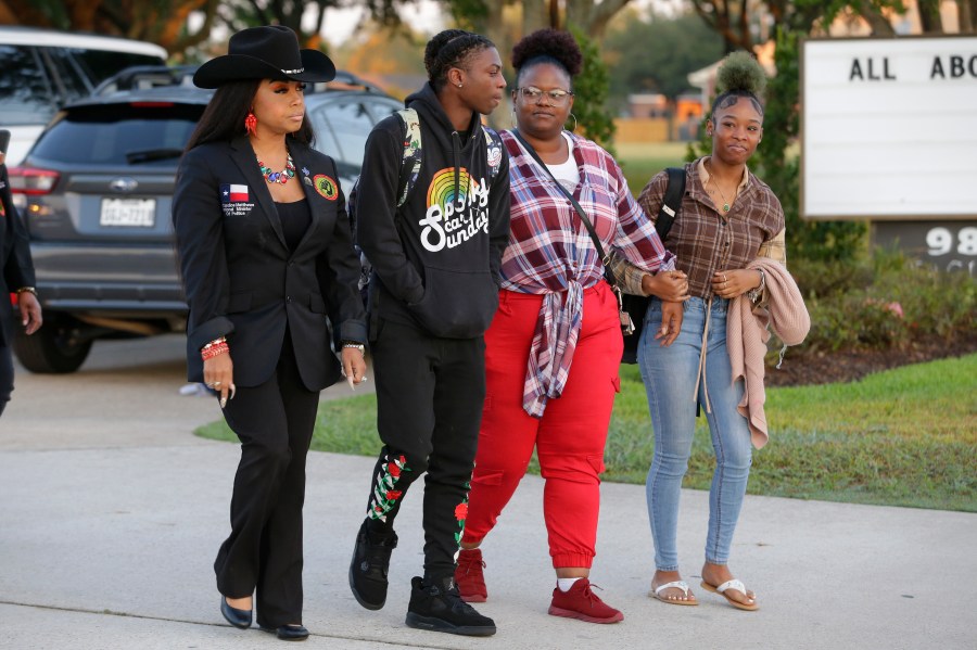 Candice Matthews, left, National minister of politics for the New Black Panther Nation; Darryl George, center left, a 17-year-old junior, and his mother Darresha George, center right, and a unidentified female, right, begin their walk across the street to go into Barbers Hill High School after Darryl served a 5-day in-school suspension for not cutting his hair Monday, Sept. 18, 2023, in Mont Belvieu. (AP Photo/Michael Wyke)