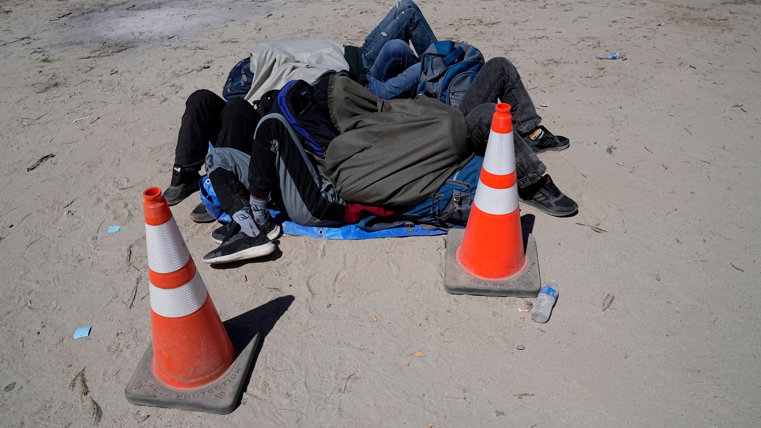 Asylum-seekers wait in a makeshift camp after crossing the nearby border with Mexico, Wednesday, Sept. 20, 2023, near Jacumba Hot Springs, Calif. Migrants continue to arrive to desert campsites along California's border with Mexico, as they await processing in tents made from tree branches. (AP Photo/Gregory Bull)