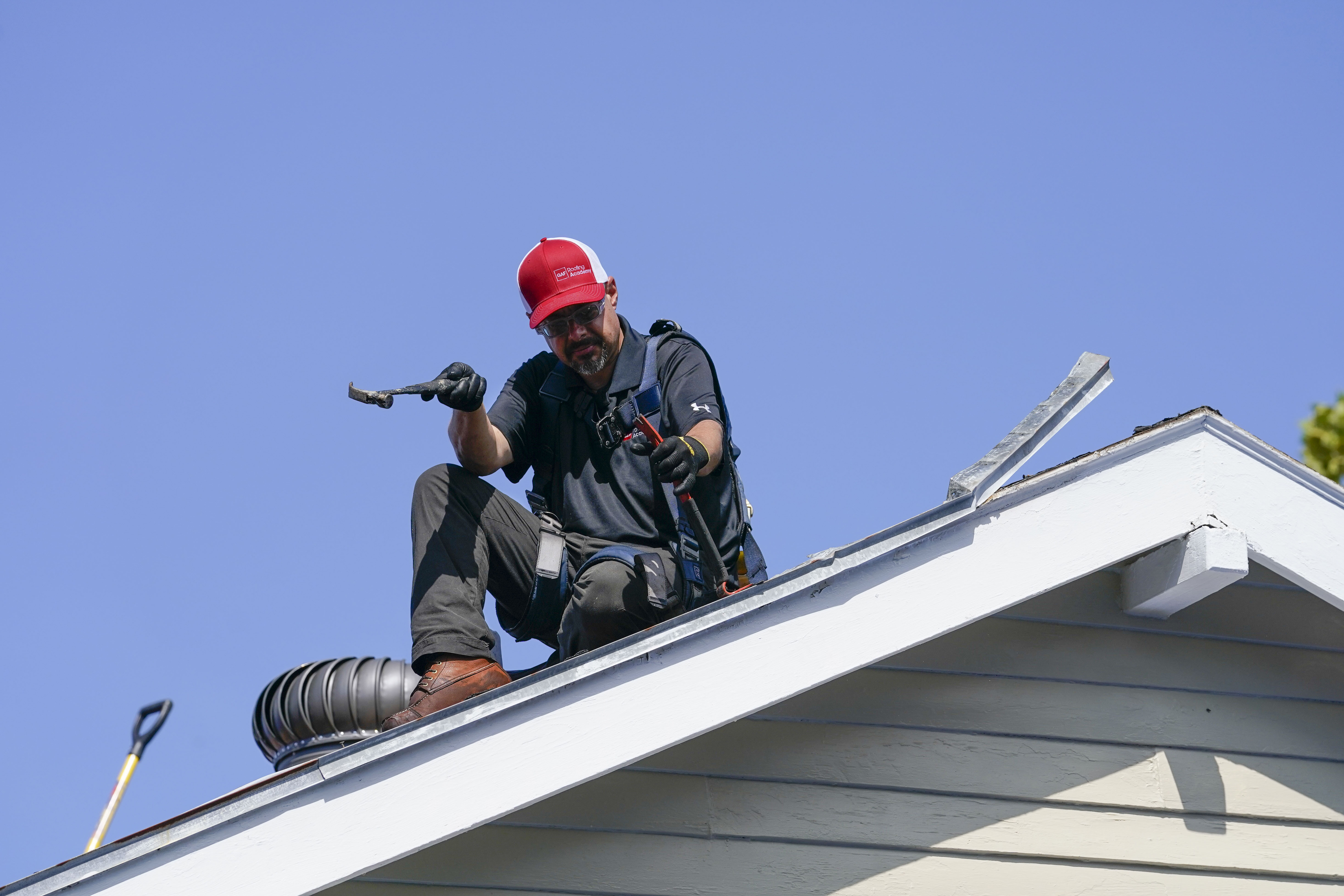 A volunteer from the GAF Roofing Academy helps replace the roof of Joe Capers, who has lived in New Orleans since the 1950s, in New Orleans, Tuesday, Sept. 12, 2023. (AP Photo/Gerald Herbert)