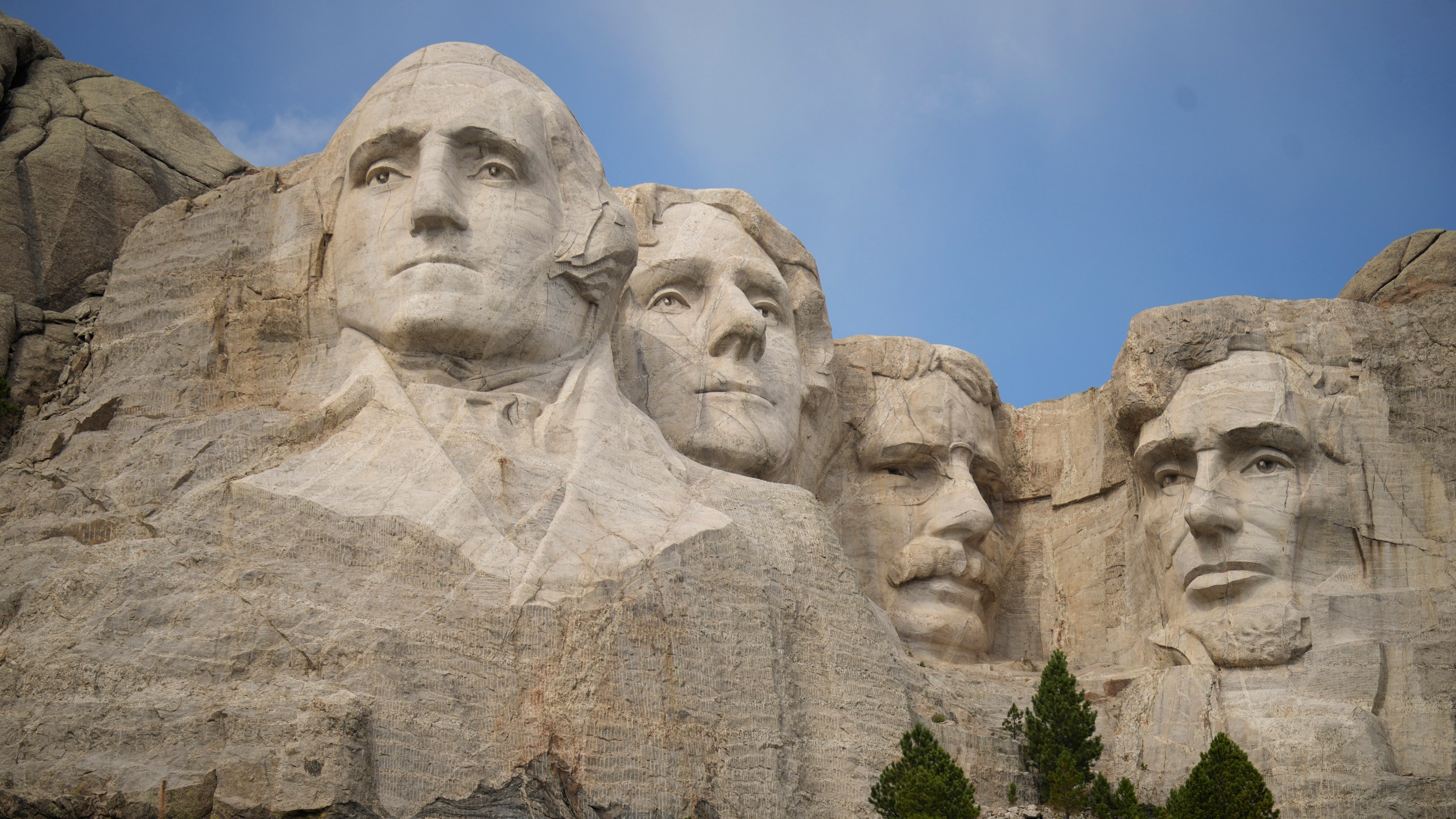 FILE - Visitors take in the massive sculpture carved into Mount Rushmore at the Mount Rushmore National Memorial Thursday, Sept. 21, 2023, in, Keystone, S.D. Gates will be locked and thousands of rangers will be furloughed from national park sites if Congress doesn’t reach a budget agreement Sunday, Oct. 1, 2023. But Arizona and Utah officials say they’ll make sure visitors can still enjoy the dramatic depths of the Grand Canyon and the soaring red cliffs of Zion Valley and South Dakota says it will pay to keep Mount Rushmore and Badlands accessible. (AP Photo/David Zalubowski, File)