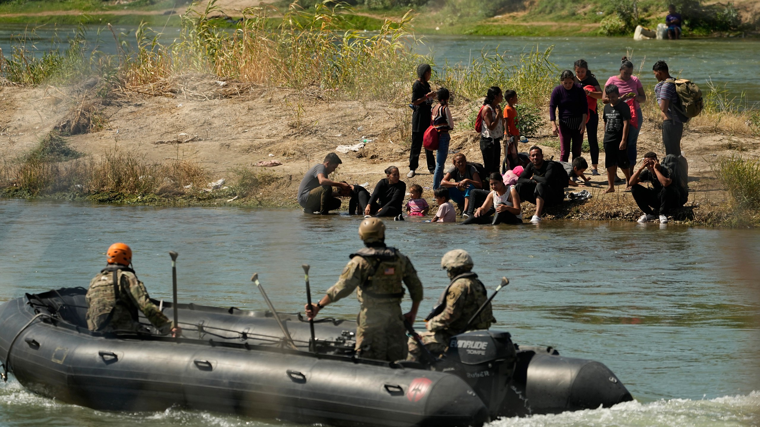 Guardsmen encourage migrants waiting on a sand bar to turn around as they attempt cross the Rio Grande from Mexico into the U.S., Saturday, Sept. 23, 2023, in Eagle Pass, Texas. (AP Photo/Eric Gay)