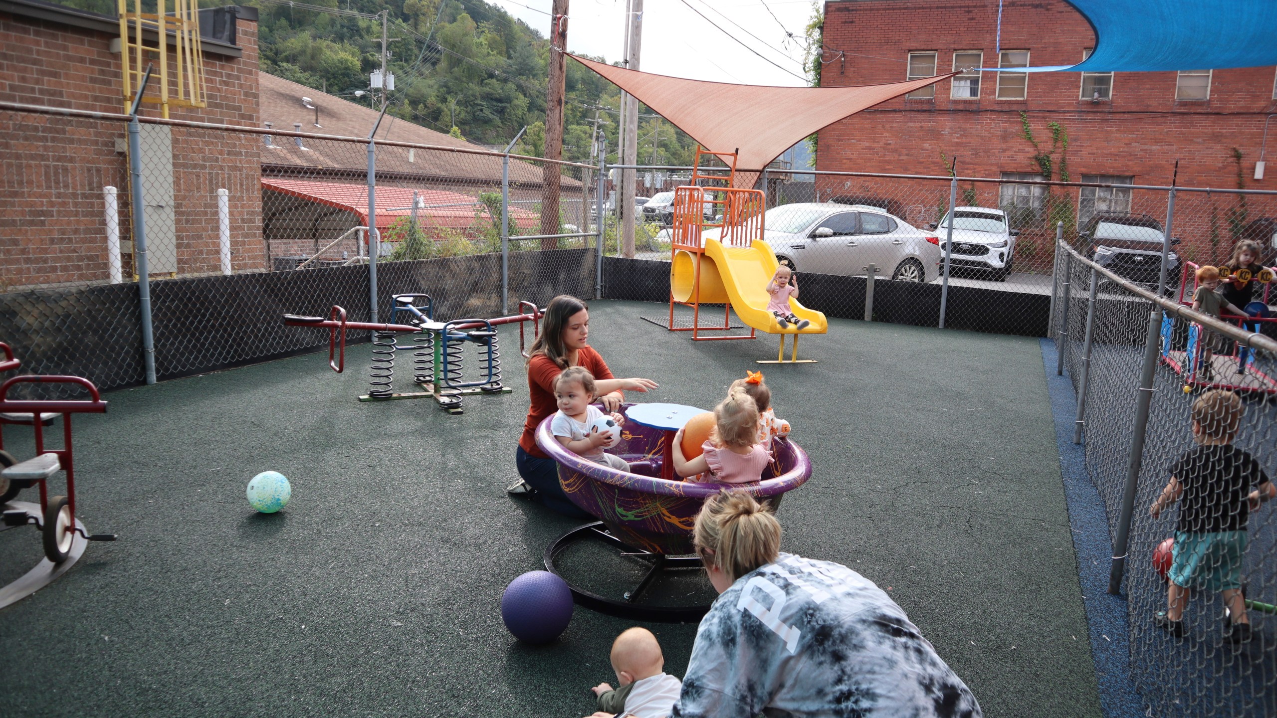 Daycare staff member Caitlyn Hammonds pushes toddlers on a teacup merry-go-round playground toy at Living Water Child Care and Learning Center in Williamson, W.Va. on Monday, Sept. 25, 2023. (AP Photo/Leah Willingham)