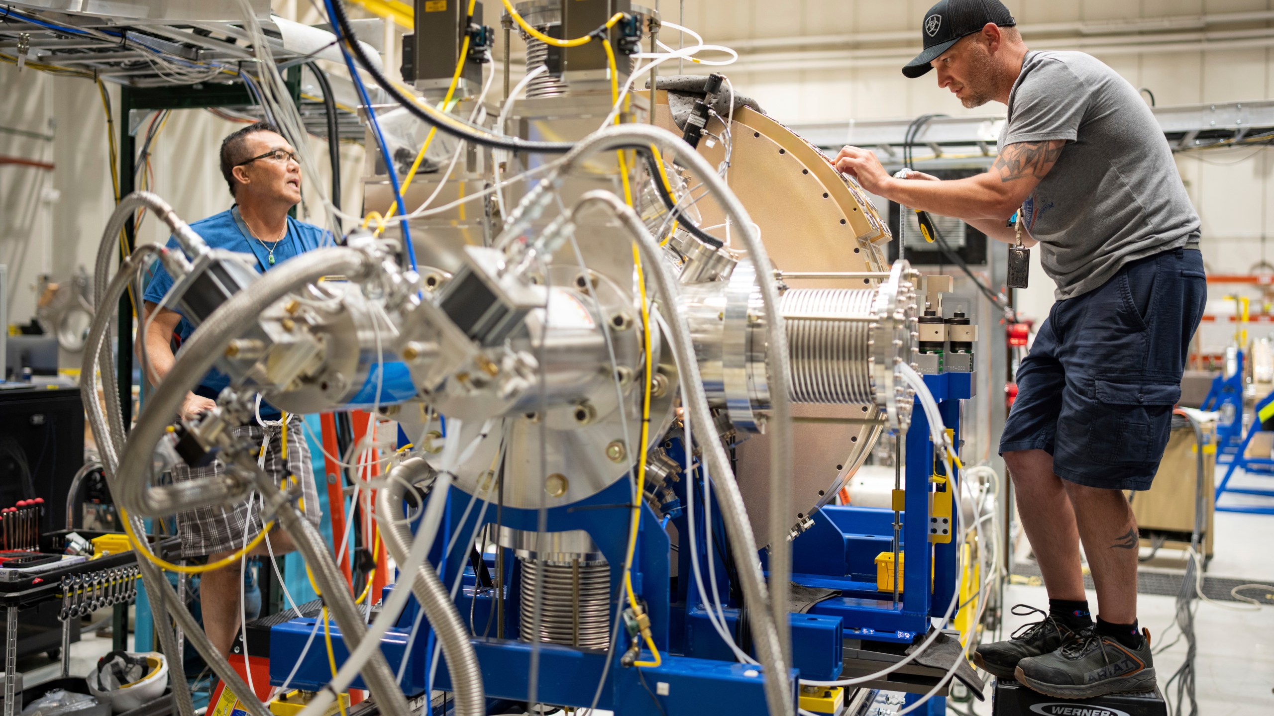 In this photo provided by Sandia National Laboratories, technicians work to test two of the cathode inductive voltage adder cells used in the Scorpius Injector being assembled at Sandia National Labs, June 8, 2023, in Albuquerque, N.M. Unable to physically validate the effectiveness and reliability of nuclear warheads since a 1992 underground test ban, the $1.8 billion Scorpius will allow experts to conduct subcritical experiments as early as 2027 in the atomic equivalent of a wind tunnel built for aircraft prohibited from flying. (Craig Fritz/Sandia National Laboratories via AP)