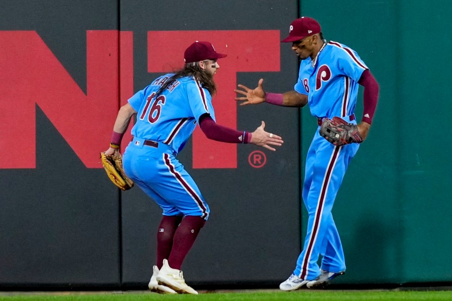 Philadelphia Phillies' Johan Rojas is congratulated by Brandon Marsh (16) after catching a long fly ball hit by Atlanta Braves' Ronald Acuna Jr. during the seventh inning of Game 4 of a baseball NL Division Series Thursday, Oct. 12, 2023, in Philadelphia. (AP Photo/Matt Rourke)