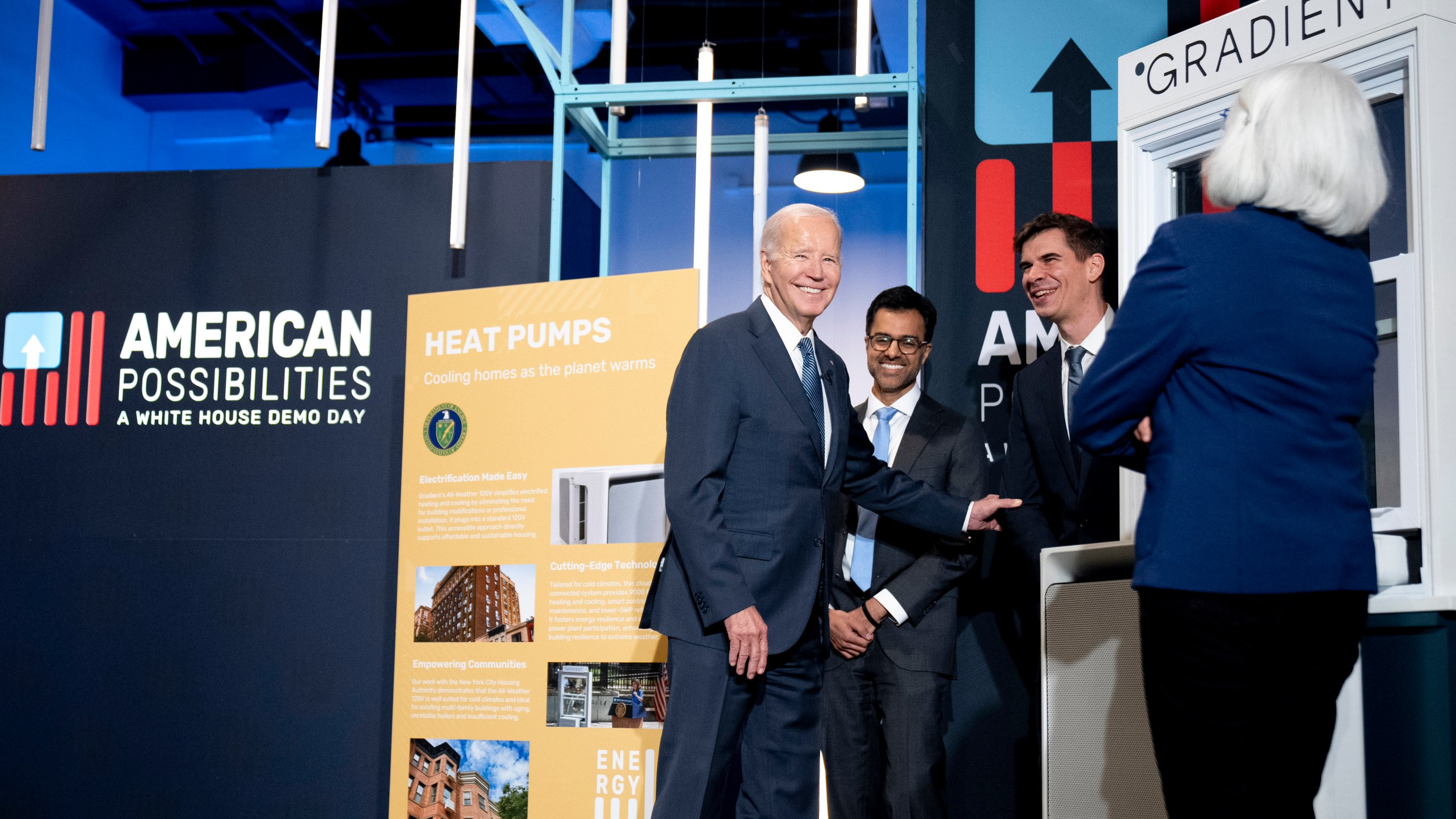 President Joe Biden laughs with Vincent Romanin, second from right, CEO of Gradient Comfort, a company that produces a window air conditioner with heat pump technology as he tours demonstrations during White House Demo Day, showcasing science and technology that have resulted from infrastructure investments, Tuesday, Nov. 7, 2023, at The Showroom in Washington. (AP Photo/Andrew Harnik)