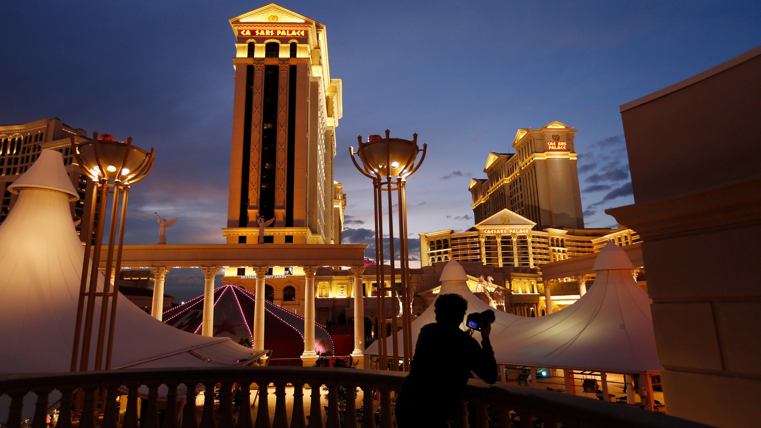 FILE - A man takes pictures of Caesars Palace hotel and casino in Las Vegas, Jan. 12, 2015. The Culinary Workers Union in Las Vegas has reached a tentative deal with casino giant Caesars Entertainment that could help avert a sweeping strike. The deal announced early Wednesday, Nov. 8, 2023, marks a major breakthrough after several months of unsuccessful negotiations. (AP Photo/John Locher, File)