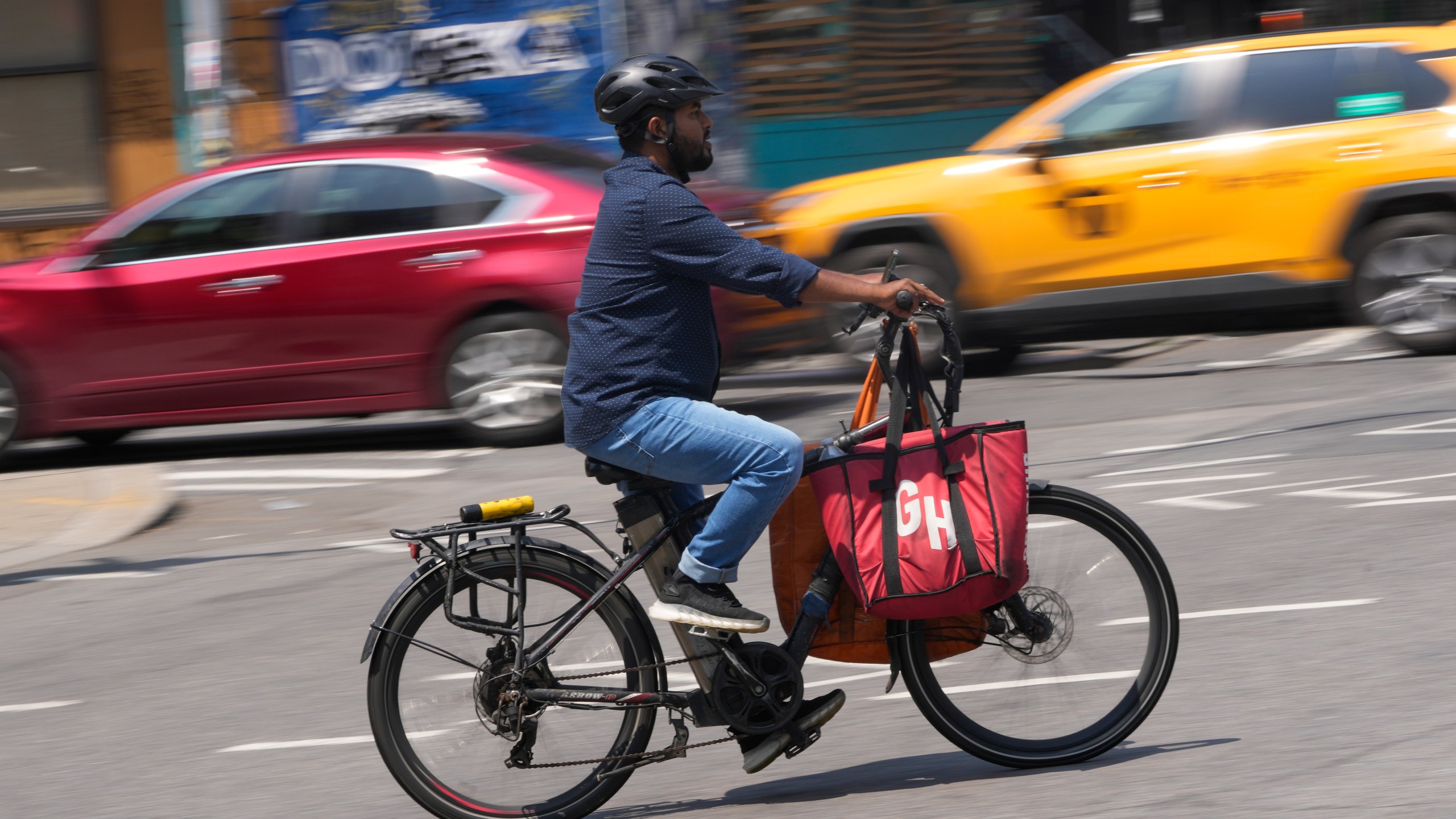 FILE - A delivery worker rides a motorized bicycle, July 25, 2023, in New York. On Monday, Nov. 13, New York City officials said that retailers and food delivery companies must do more to halt the proliferation of unsafe e-bike and e-scooter batteries after a fire blamed on an electric scooter's lithium ion battery killed three people over the weekend. (AP Photo/Seth Wenig, File)