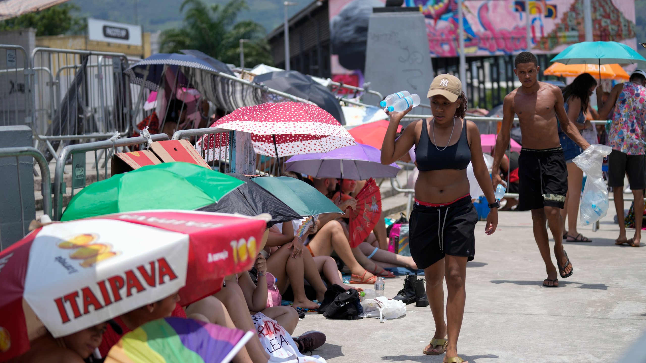 Street vendors sell bottled water to Taylor Swift fans amid a heat wave before her Eras Tour concert outside the Nilton Santos Olympic stadium in Rio de Janeiro, Brazil, Saturday, Nov. 18, 2023. A 23-year-old Taylor Swift fan died at the singer's Eras Tour concert in Rio de Janeiro Friday night, according to a statement from the show's organizers in Brazil. Both Swifties and politicians reacted to the news with outrage. While a cause of death for Ana Clara Benevides Machado has not been announced, fans complained they were not allowed to take water into Nilton Santos Olympic Stadium despite soaring temperatures. (AP Photo/Silvia Izquierdo)