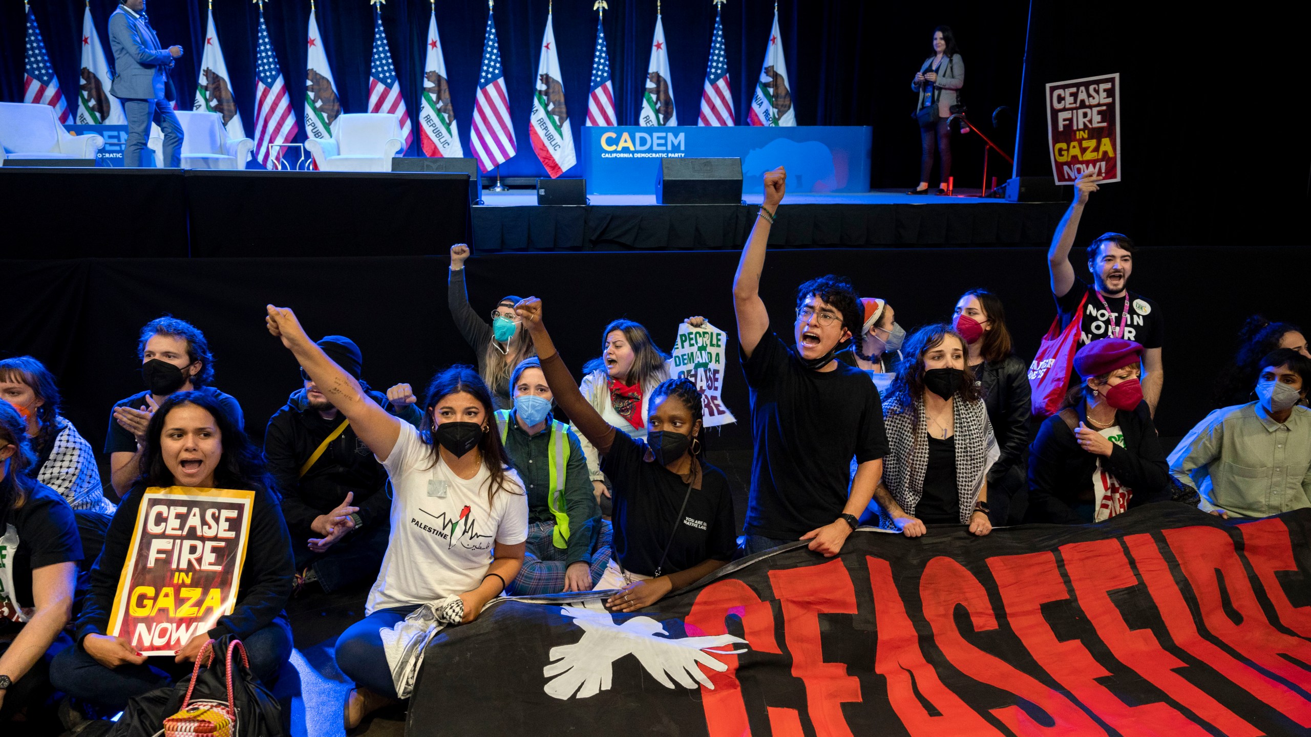 Pro-Palestinian demonstrators sit in front of the stage, disrupting the afternoon session of the 2023 California Democratic Party November State Endorsing Convention, Saturday, Nov. 18, 2023, at SAFE Credit Union Convention Center in Sacramento, Calif. (Lezlie Sterling/The Sacramento Bee via AP)