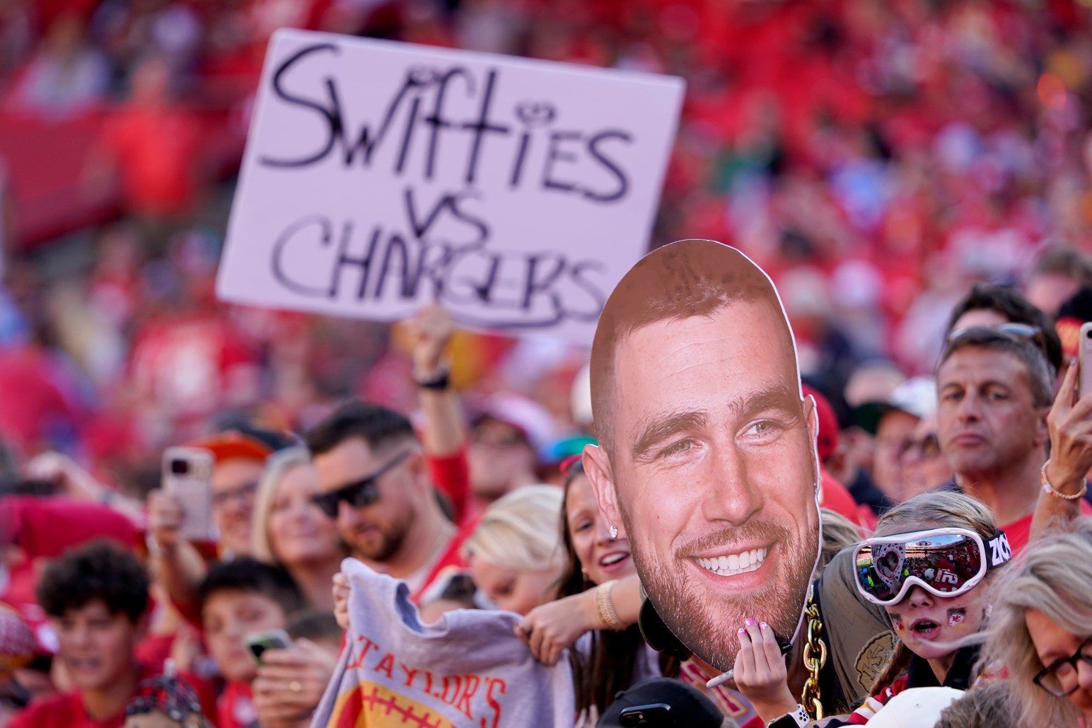 Fans hold up signs referring to Kansas City Chiefs tight end Travis Kelce and Taylor Swift before the start of an NFL football game between the Kansas City Chiefs and the Los Angeles Chargers Sunday, Oct. 22, 2023, in Kansas City, Mo. (AP Photo/Ed Zurga)