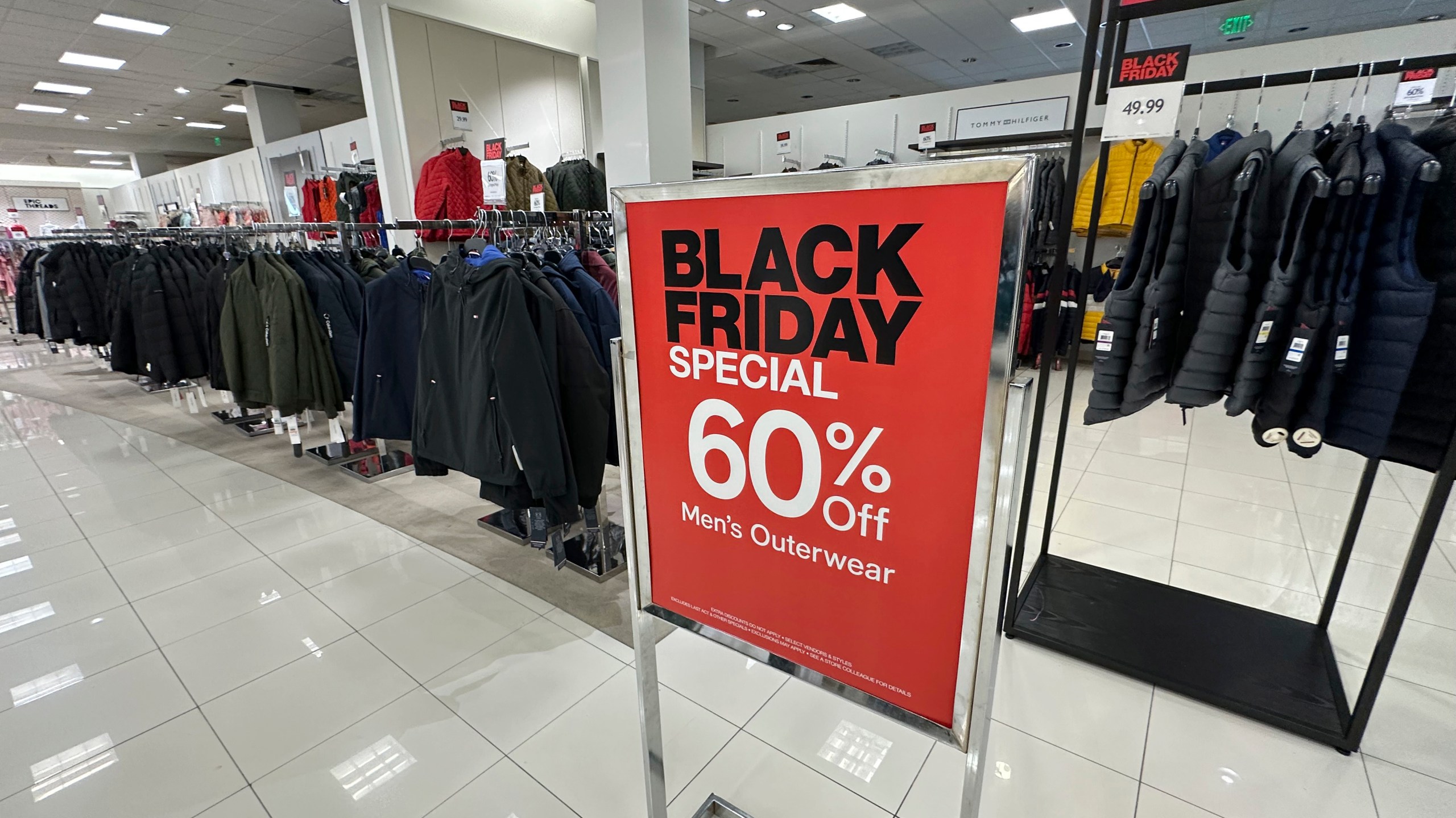 A sign notes Black Friday discount available on racks of men's outerwear in a Macy's department store on Monday, Nov. 20, 2023, in northeast Denver. While Black Friday may no longer look like the crowd-filled, in-person mayhem that it was just decades ago — in large part due to the rising dependence on online shopping that was accelerated by the COVID-19 pandemic — the holiday sales event is still slated to attract millions of consumers. (AP Photo/David Zalubowski)