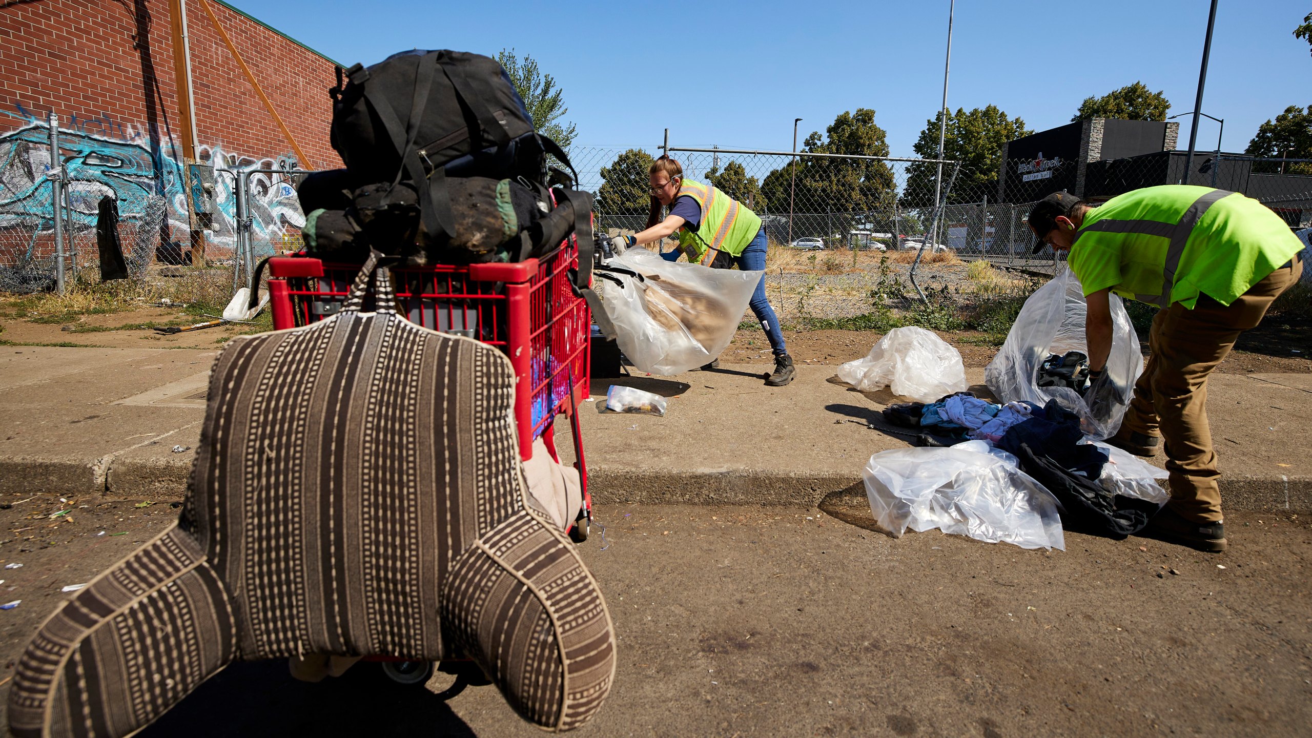 THIS CORRECTS THE NAME OF THE CONTRACTOR TO RAPID RESPONSE BIO CLEAN, NOT RAPID RESPONSE BIO CLEANUP AS ORIGINALLY SENT - Amber Nastasia, left, and Jacob Miller from Rapid Response Bio Clean clean a homeless camp in Portland, Ore., Thursday, July 27, 2023. Cities across the U.S. are struggling with and cracking down on tent encampments as the number of homeless people grows, largely due to a lack of affordable housing. Homeless people and their advocates say sweeps are cruel and costly, and there aren't enough homes or beds for everyone. (AP Photo/Craig Mitchelldyer)