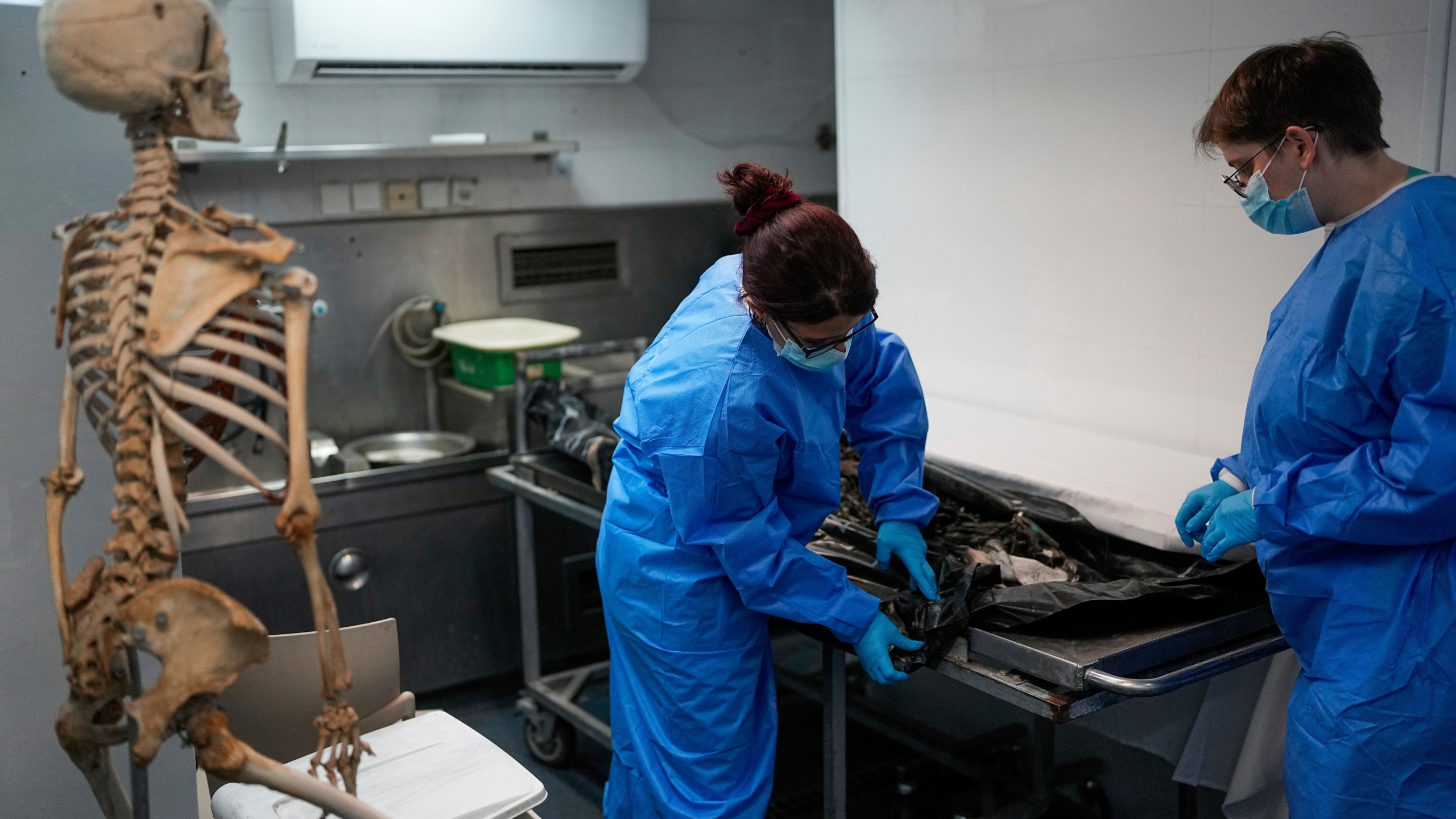 FILE - Israeli forensic experts work on bodies of Israelis killed by Hamas militants in the National Center for Forensic Medicine in Tel Aviv, Israel on Oct. 18, 2023. Nearly two months after Hamas infiltrated Israel, killing some 1,200 people and taking about 240 hostage, dozens are still unaccounted for, their families left living in limbo. (AP Photo/Ohad Zwigenberg, File)