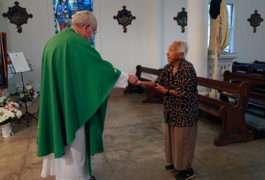 The Rev. Patrick Killilea gives communion to Meli Watanuki, at Mass on Wednesday, July 19, 2023, in Kalaupapa, Hawaii. In the 1800s, the peninsula was a settlement for banished leprosy patients, later called Hansen's disease. (AP Photo/Jessie Wardarski)