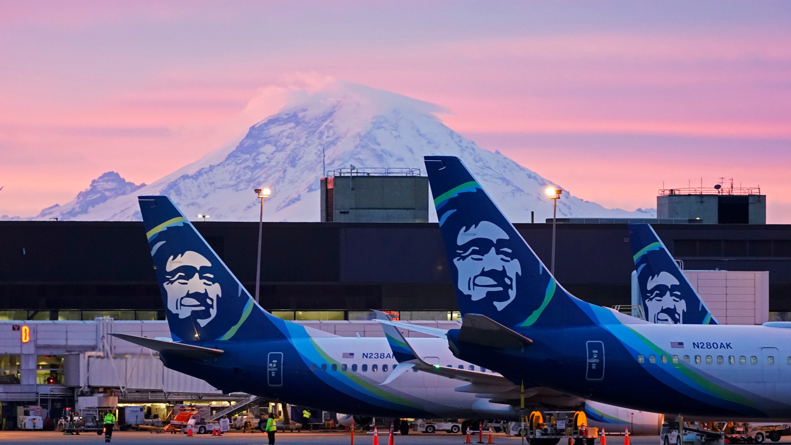 FILE - Alaska Airlines planes are shown parked at gates with Mount Rainier in the background at sunrise, March 1, 2021, at Seattle-Tacoma International Airport in Seattle. Alaska Air Group said Sunday, Dec. 3, 2023, that it agreed to buy Hawaiian Airlines in a $1 billion deal. (AP Photo/Ted S. Warren, File)