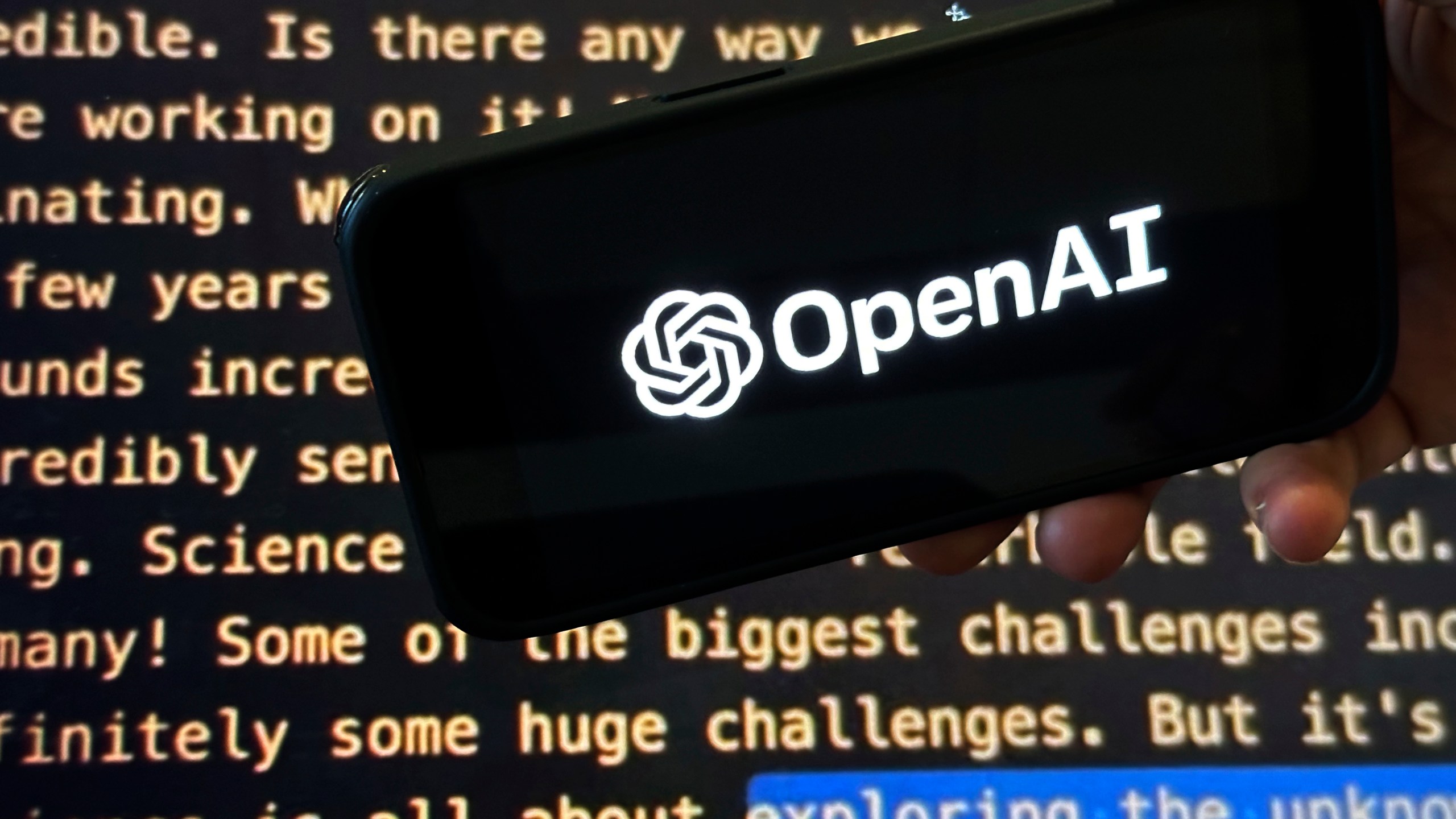 File - The OpenAI logo appears on a mobile phone in front of a screen showing part of the company website in this photo taken on Nov. 21, 2023 in New York. Negotiators will meet this week to hammer out details of European Union artificial intelligence rules but the process has been bogged down by a simmering last-minute battle over how to govern systems that underpin general purpose AI services like OpenAI's ChatGPT and Google's Bard chatbot. (AP Photo/Peter Morgan, File)