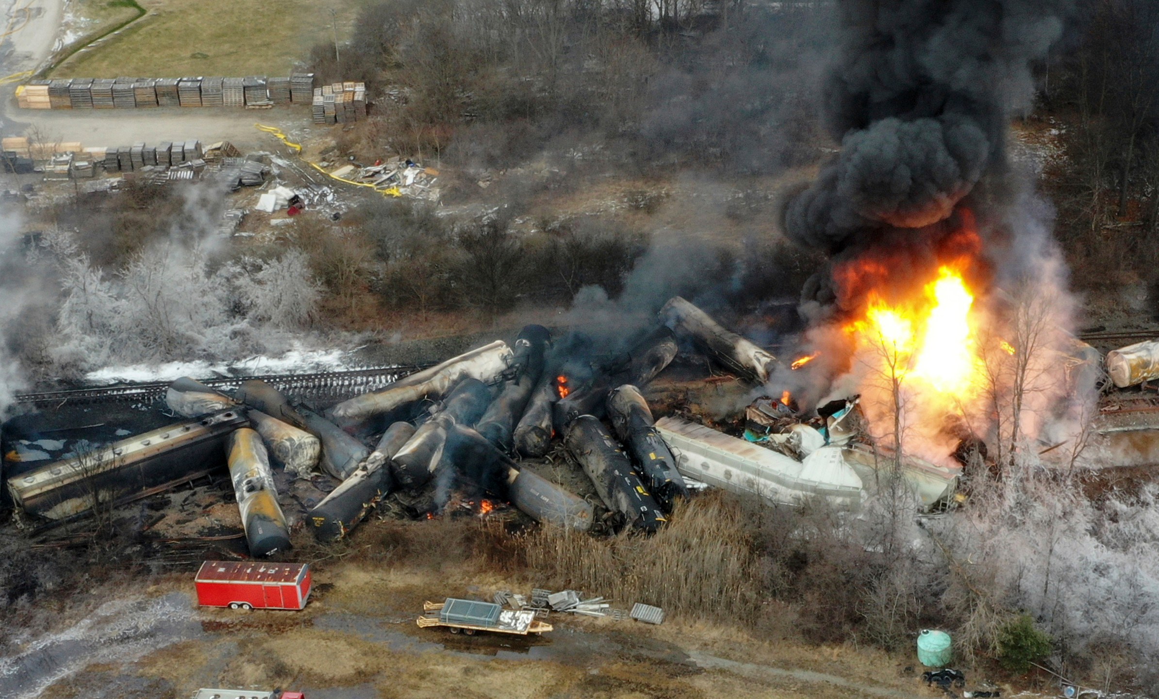 FILE - Portions of a Norfolk Southern freight train that derailed the night before burn in East Palestine, Ohio, Feb. 4, 2023. Norfolk Southern railroad announced on Tuesday, Dec. 4, plans to stop paying relocation aid to people displaced by the derailment right after the one-year anniversary of the crash. Railroad officials reiterated their long-term commitment to helping the town of East Palestine and the surrounding area recover. (AP Photo/Gene J. Puskar, File)